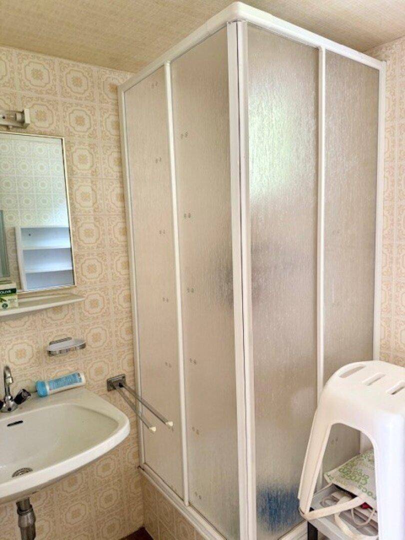 Badezimmer mit Duschkabine, Waschbecken und gemusterten Fliesen im Retro-Stil.