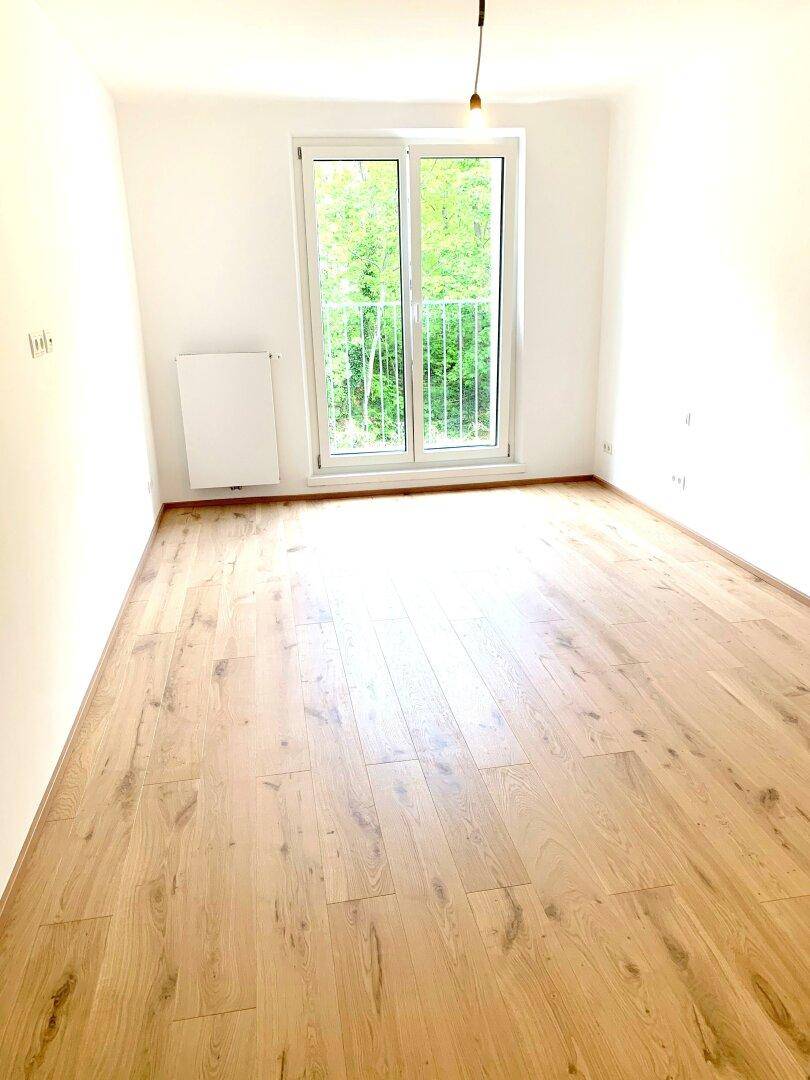 Helles Schlafzimmer mit Parkettboden und französischem Balkon, bereit zum Einzug.