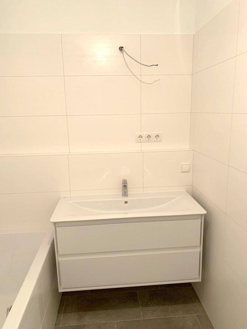 Neuer Waschtisch mit Unterschrank in einem hell gefliesten Badezimmer.