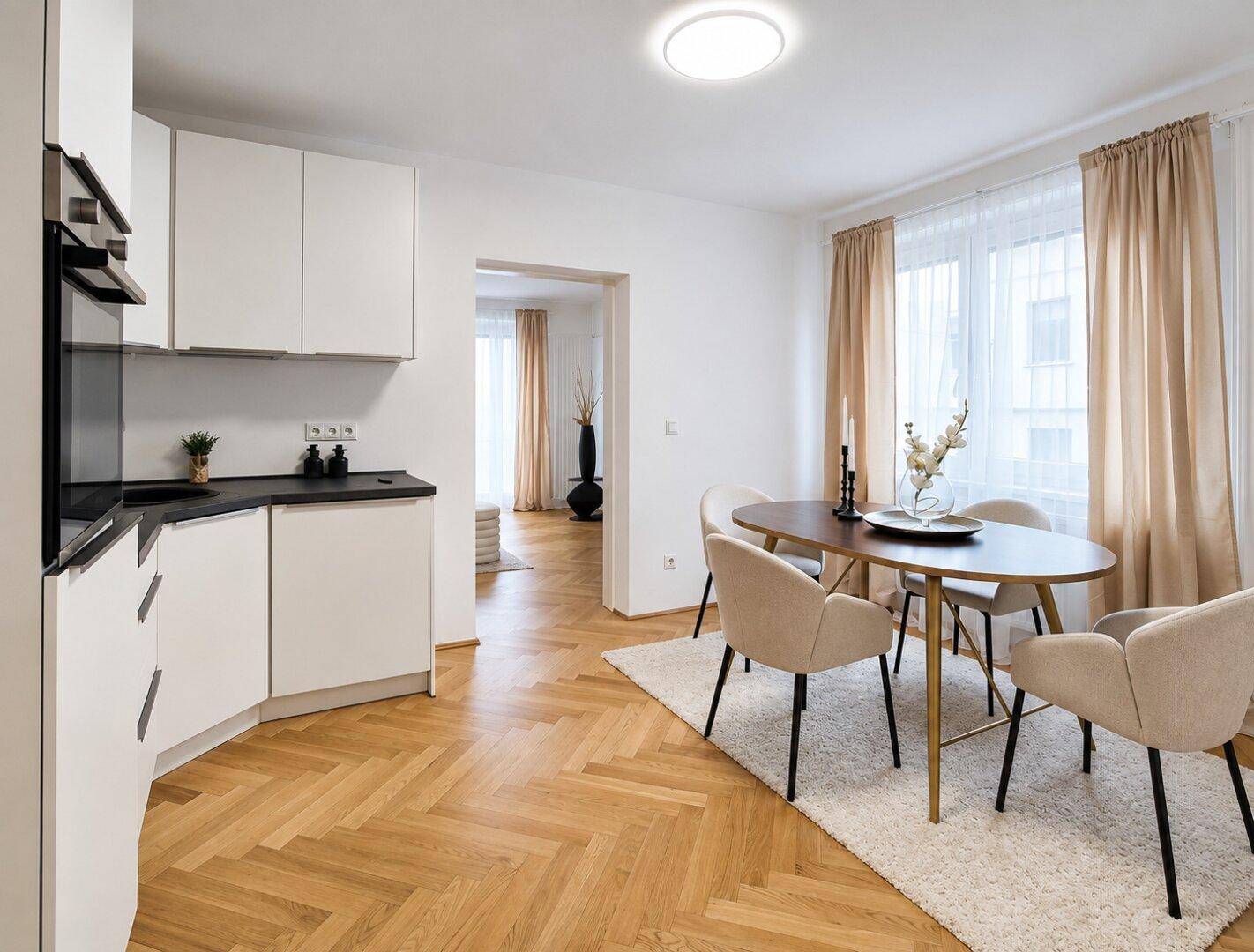 Heller Essbereich mit modernem Holztisch, beigen Stühlen und Blick in die angrenzende Küche.