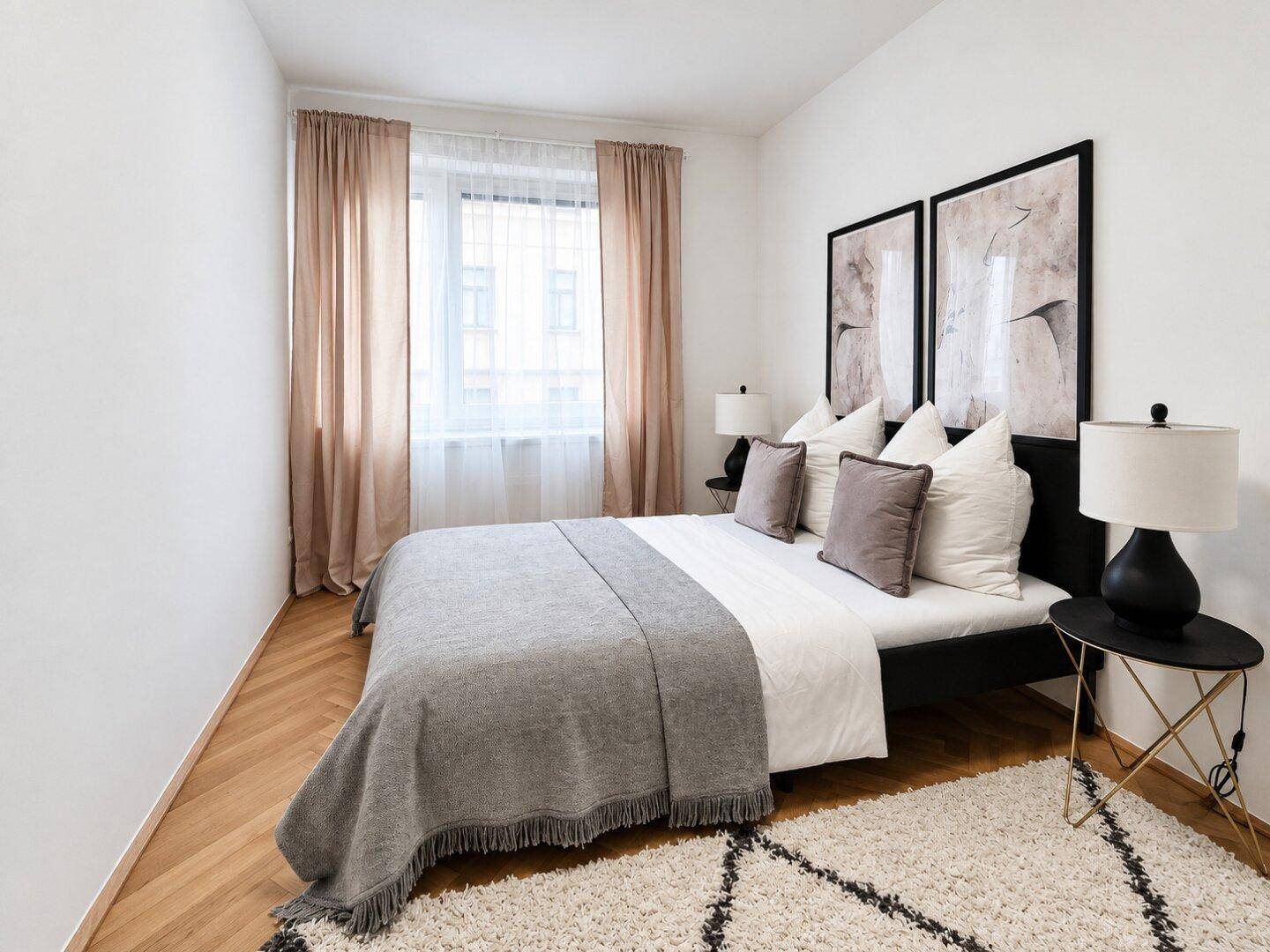 Modernes Schlafzimmer mit Doppelbett, beigen Vorhängen und Fischgrätparkettboden.
