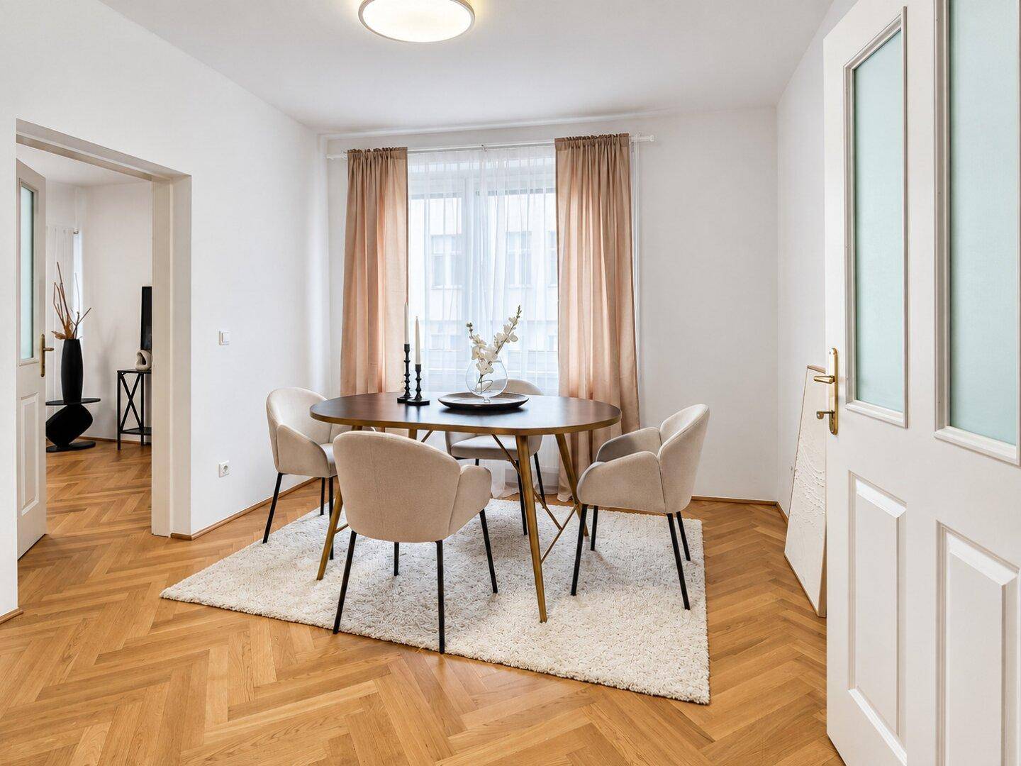 Heller Essbereich mit ovalem Holztisch, beigen Stühlen und Blick in den Wohnbereich.