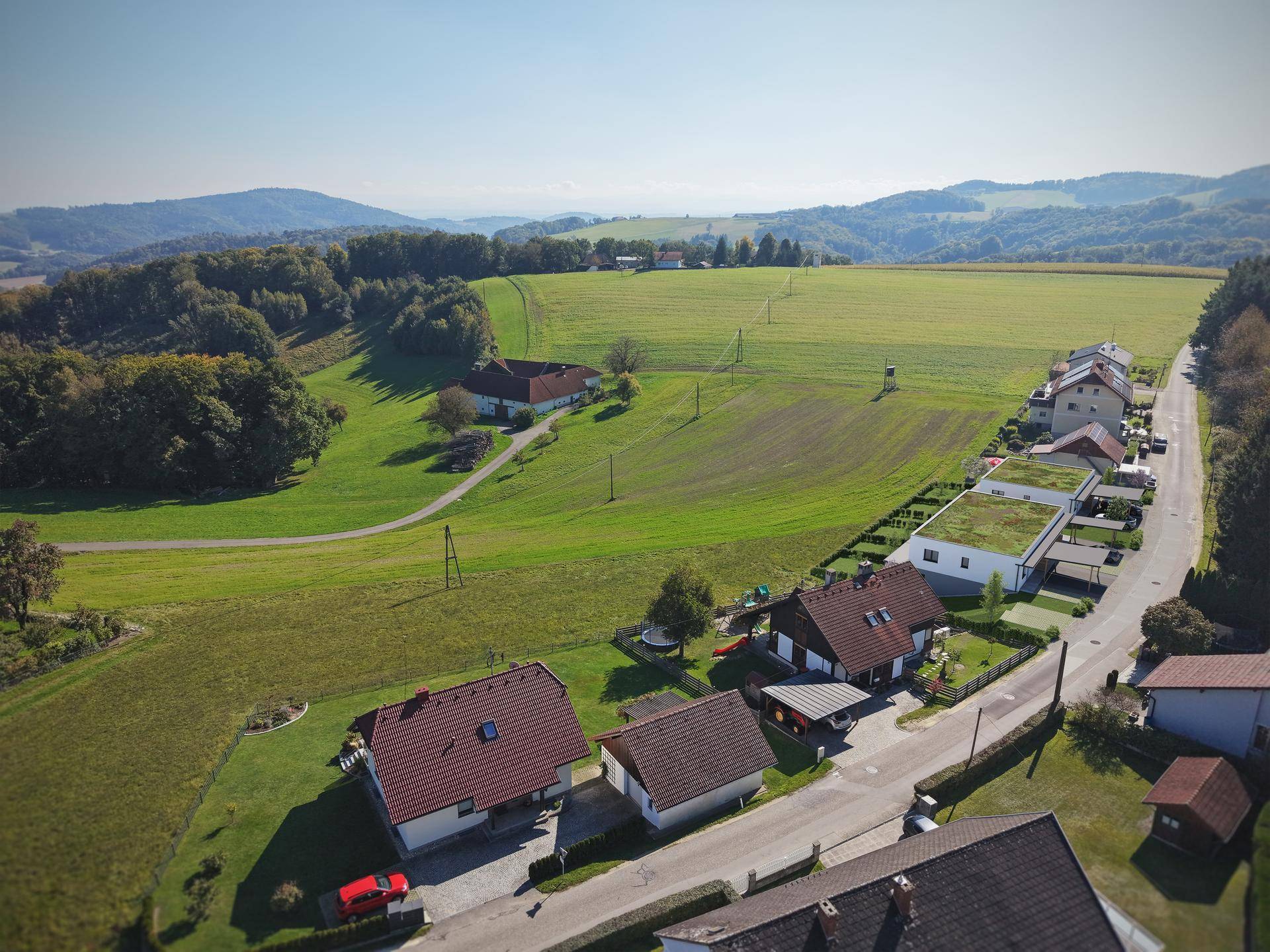 Luftaufnahme einer ländlichen Siedlung mit Häusern und weiten Feldern.