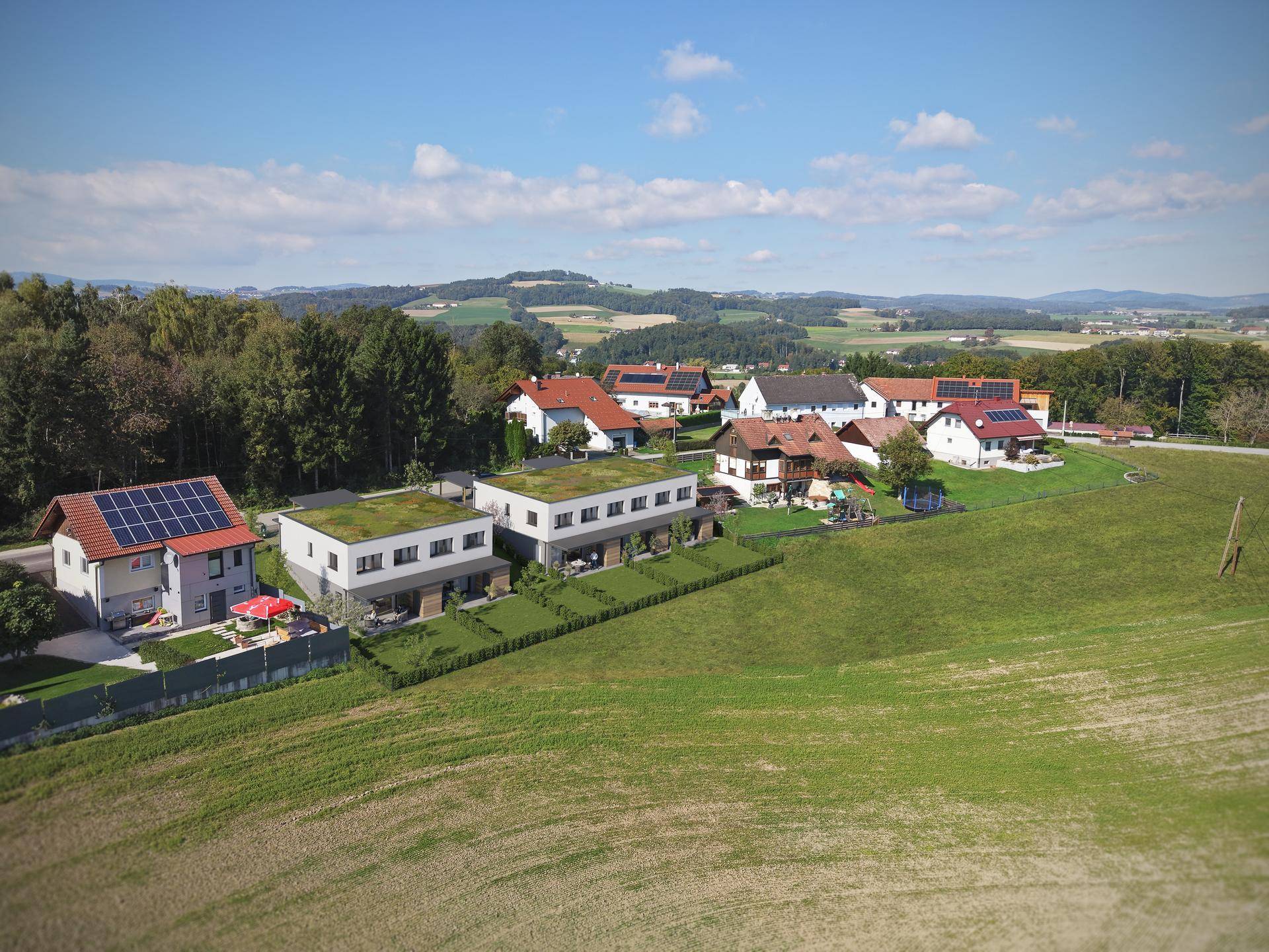 Weitläufige Luftaufnahme der neuen Reihenhäuser eingebettet in die ländliche Landschaft.