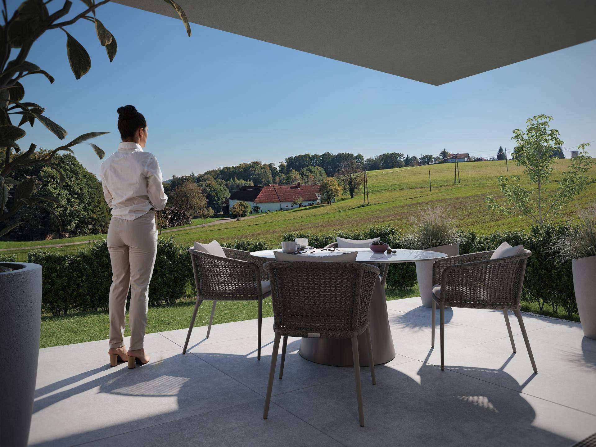 Sonnige Terrasse mit Sitzgelegenheiten und weitem Blick über die grüne Landschaft.