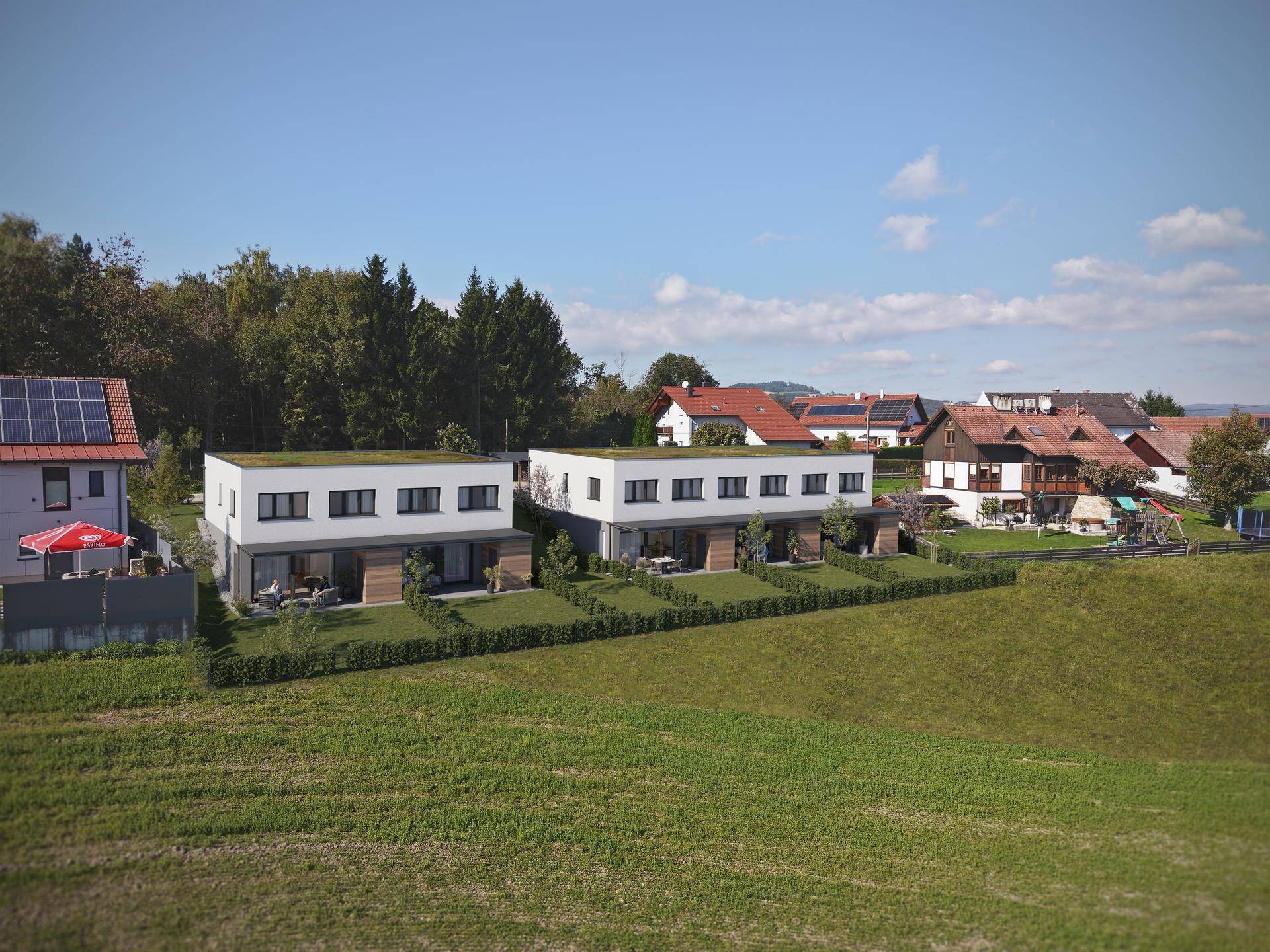 Luftaufnahme der modernen Reihenhäuser mit Flachdach und Gärten in ländlicher Umgebung.