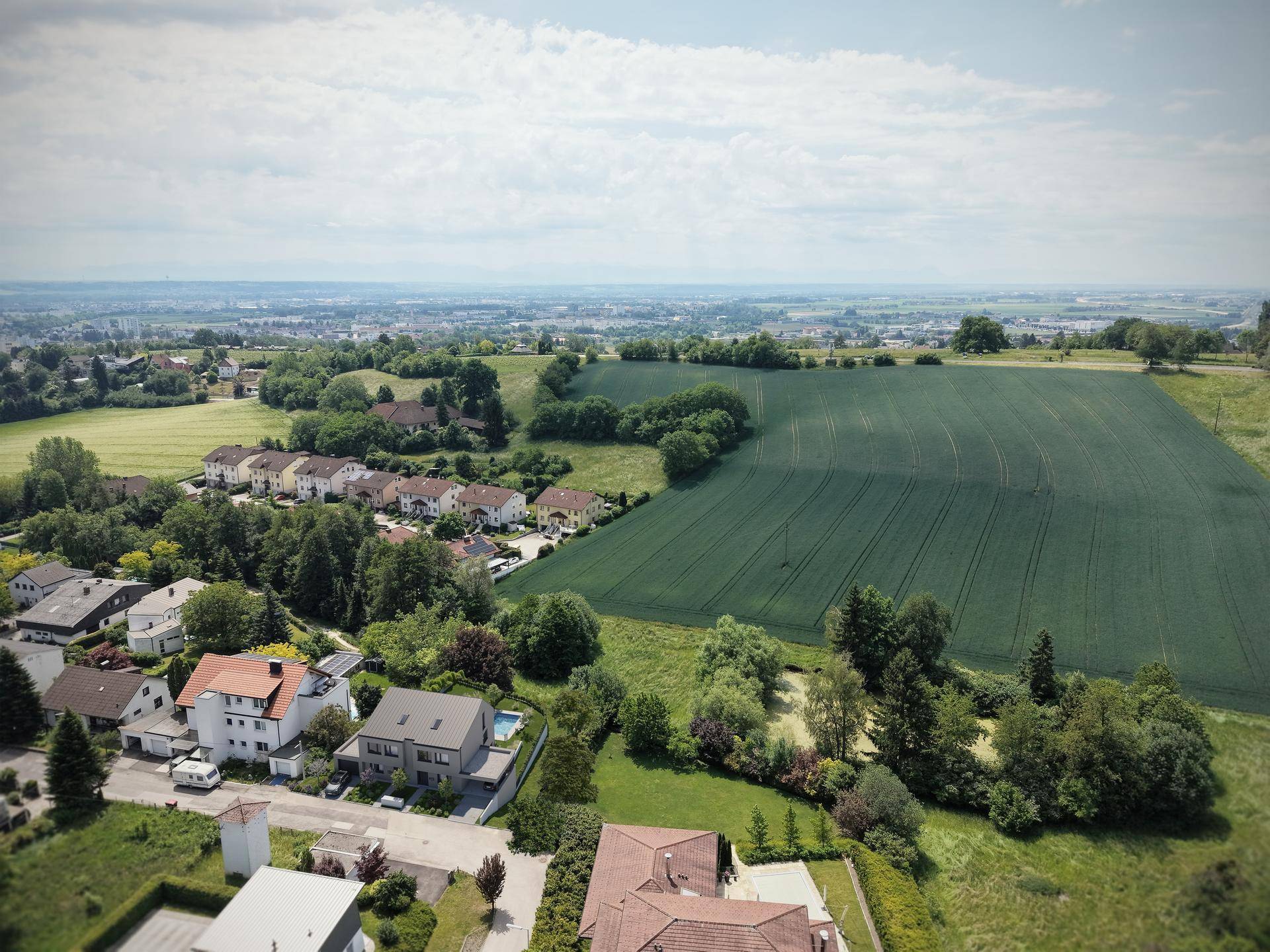 Luftaufnahme einer ländlichen Wohngegend mit weiten Feldern und Siedlungen.