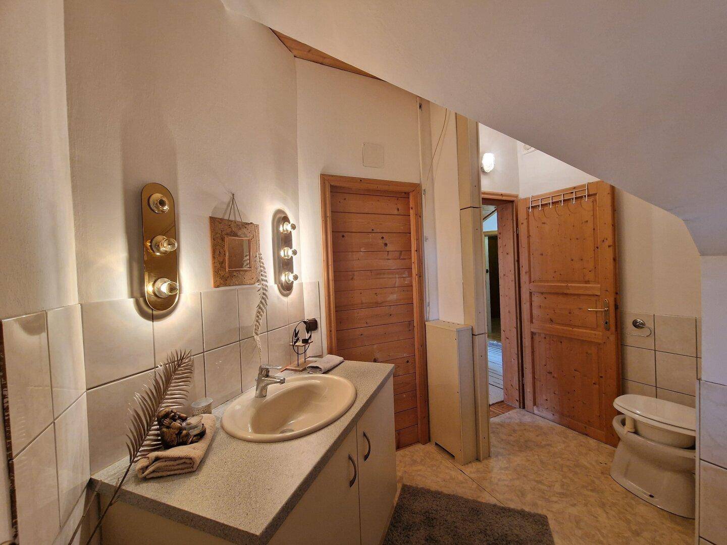 Badezimmer mit Waschbecken, Spiegelschrank und Fliesen an den Wänden im Dachgeschoss.