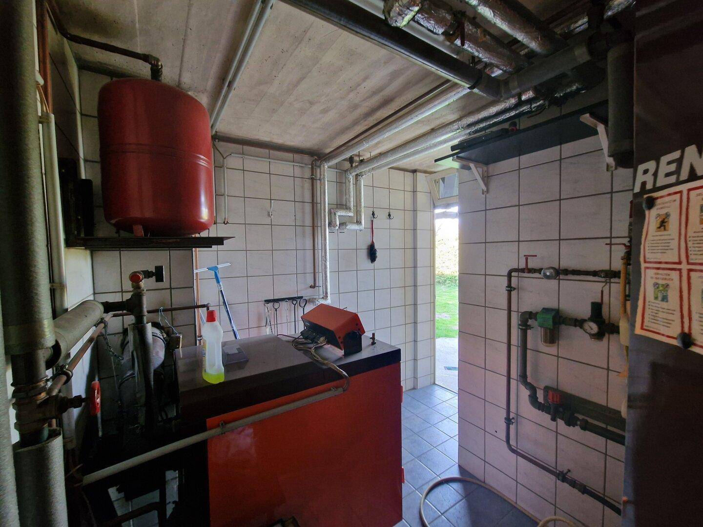 Heizungsraum mit Boiler, Rohren und technischen Installationen für die Wärmeversorgung.