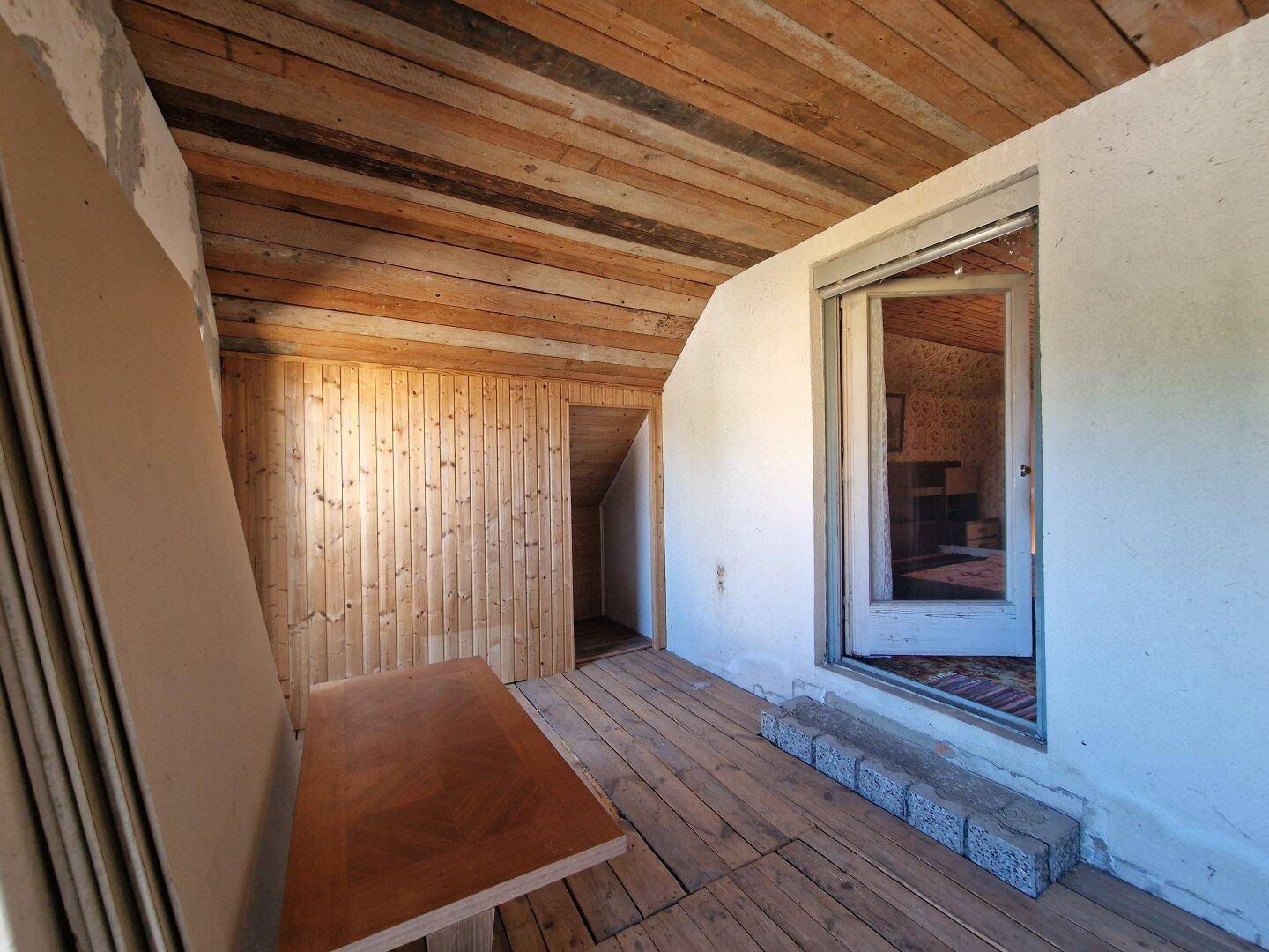 Dachbodenraum mit Holzboden und Holzdecke, bietet Stauraum und Zugang zu einem weiteren Bereich.