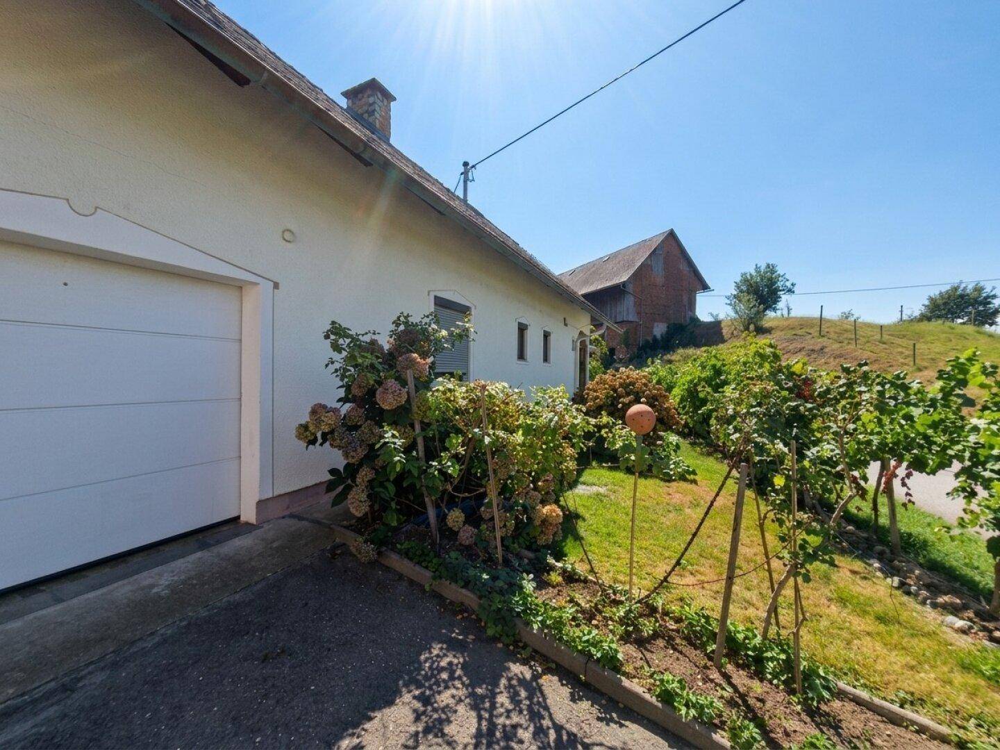 Seitenansicht des Hauses mit Garage, gepflegtem Gartenbereich und sonniger Ausrichtung.