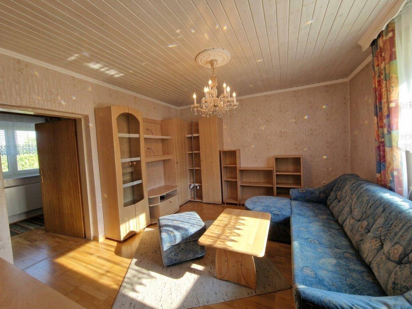 Geräumiges Wohnzimmer mit Holzboden, Sofa, Schränken und Kronleuchter.