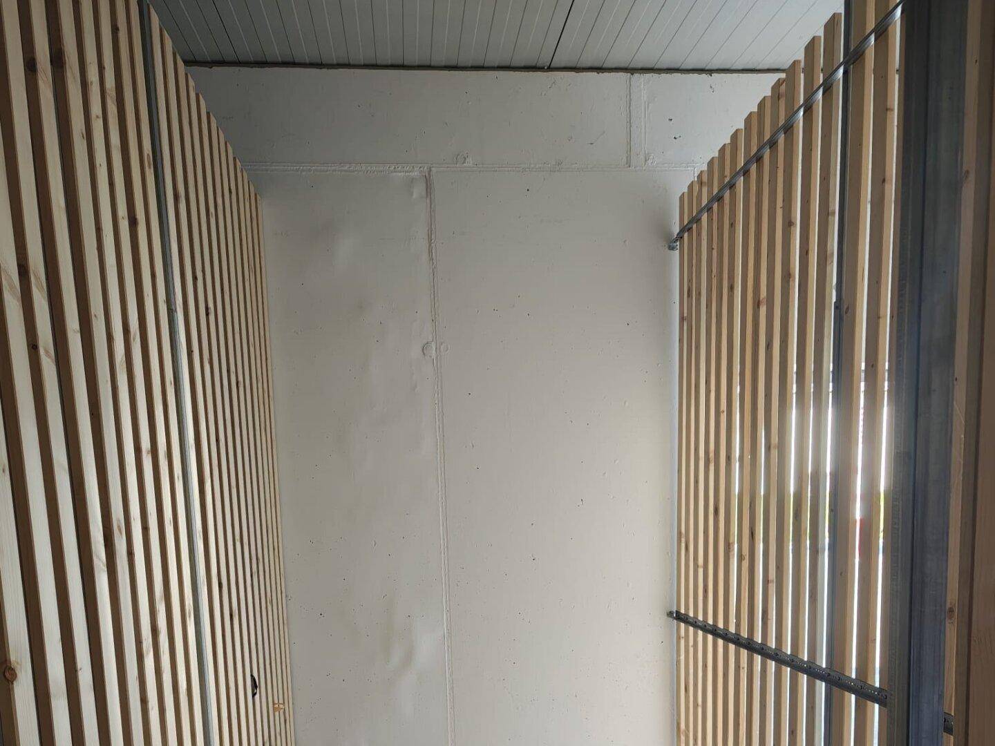 Lagerraum mit Holzlattenwänden und einfachem Betonboden, ideal für Abstellzwecke.