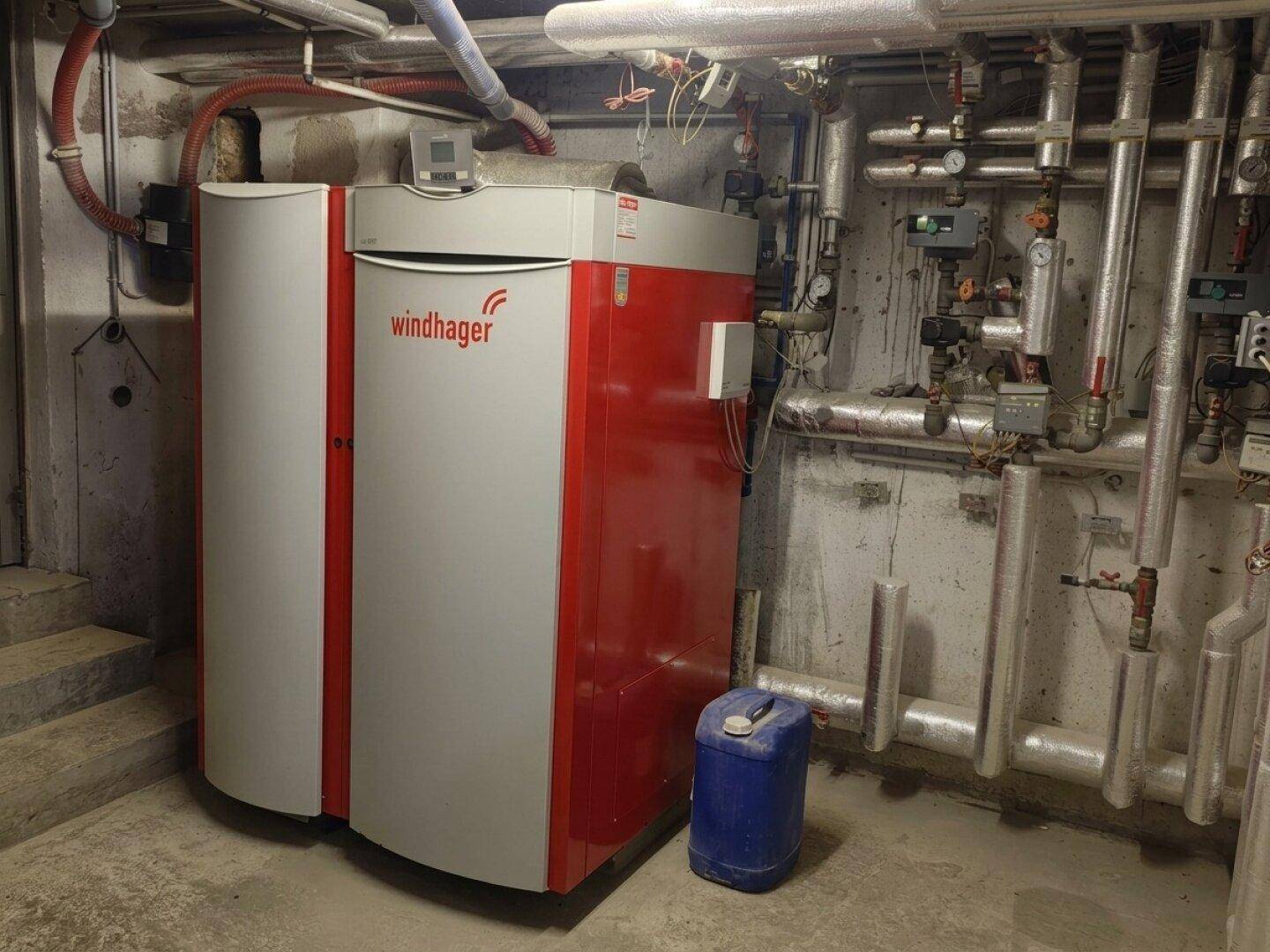 Heizungsraum mit einem modernen Windhager Heizsystem und zahlreichen Rohrleitungen.
