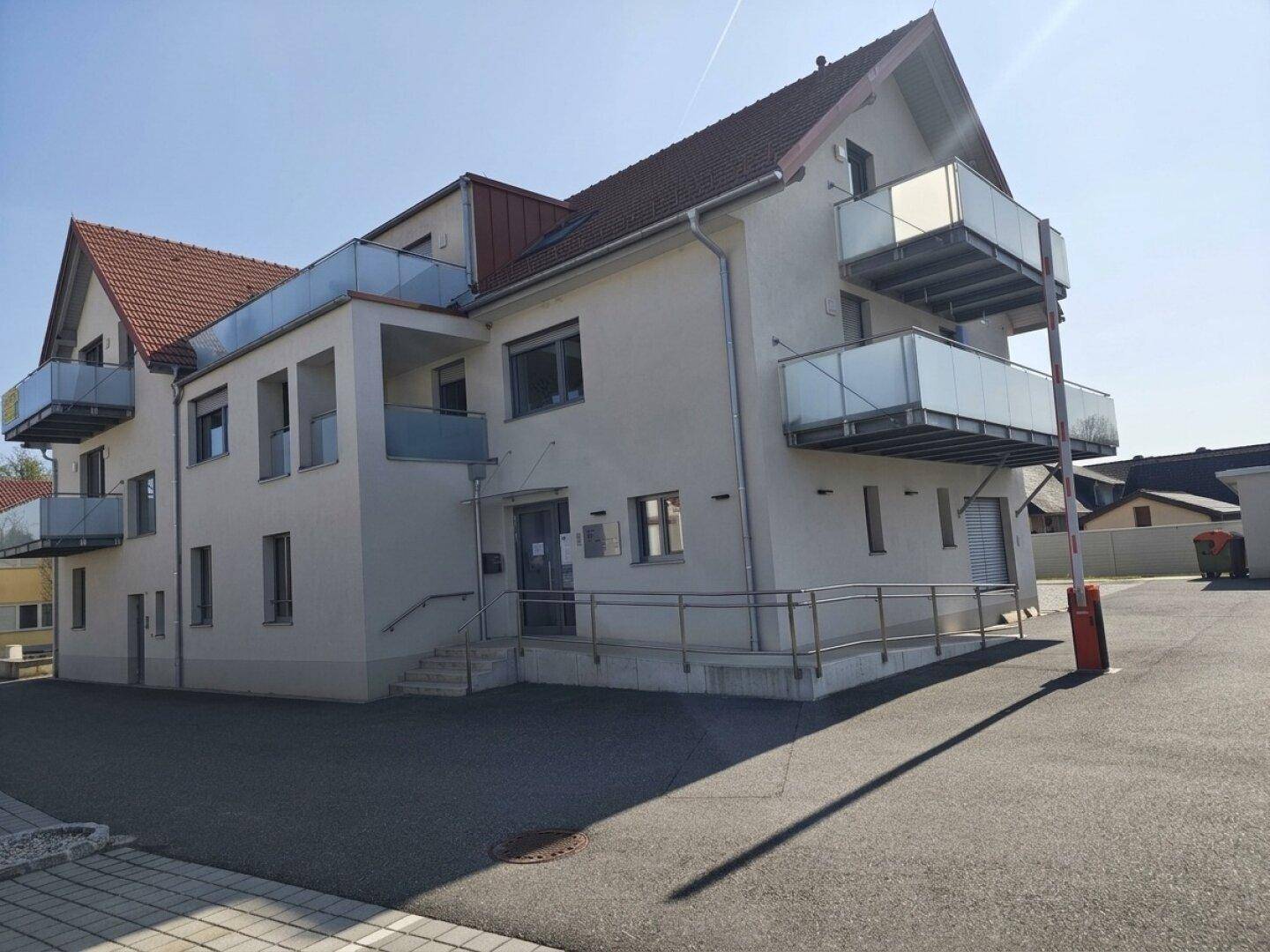 Seitenansicht des Gebäudes mit mehreren Balkonen, Rampe und Zufahrt zum Parkplatz.