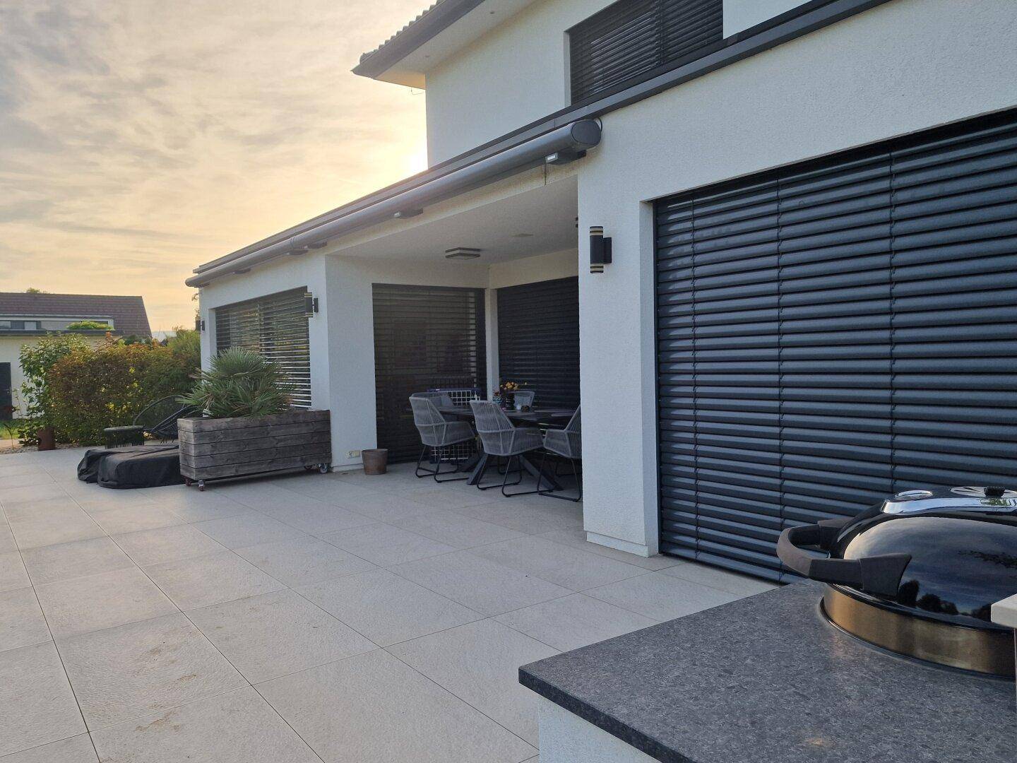 Große Terrasse mit Außenküche, Grillbereich und elektrischer Markise am Haus.