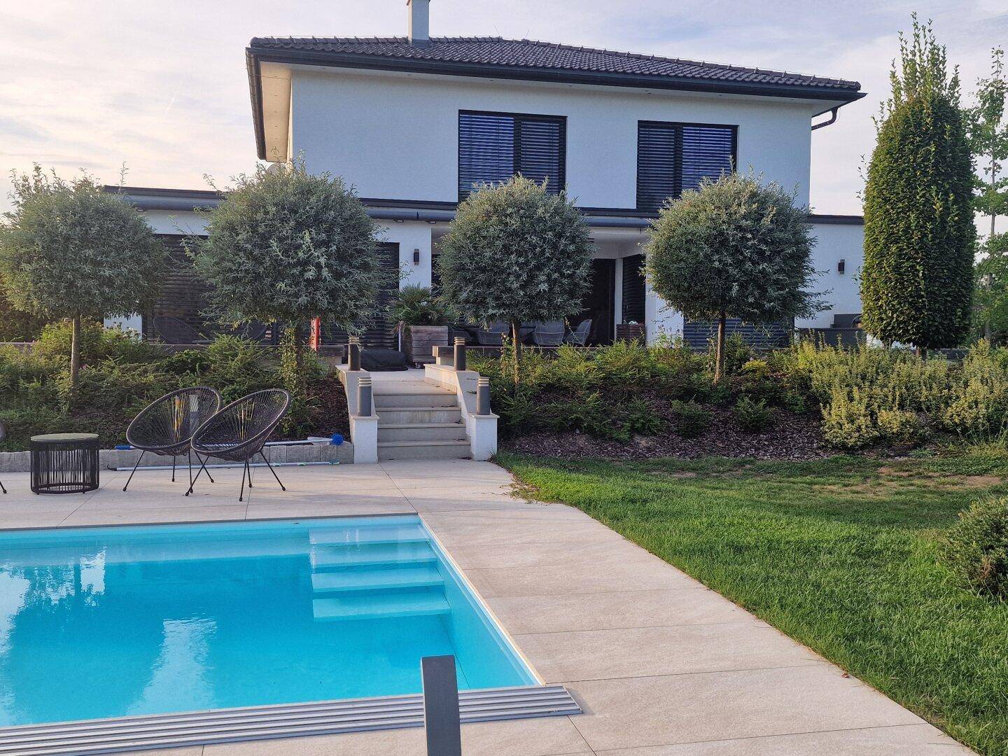 Modernes Einfamilienhaus mit großem Swimmingpool und gepflegtem Gartenbereich.