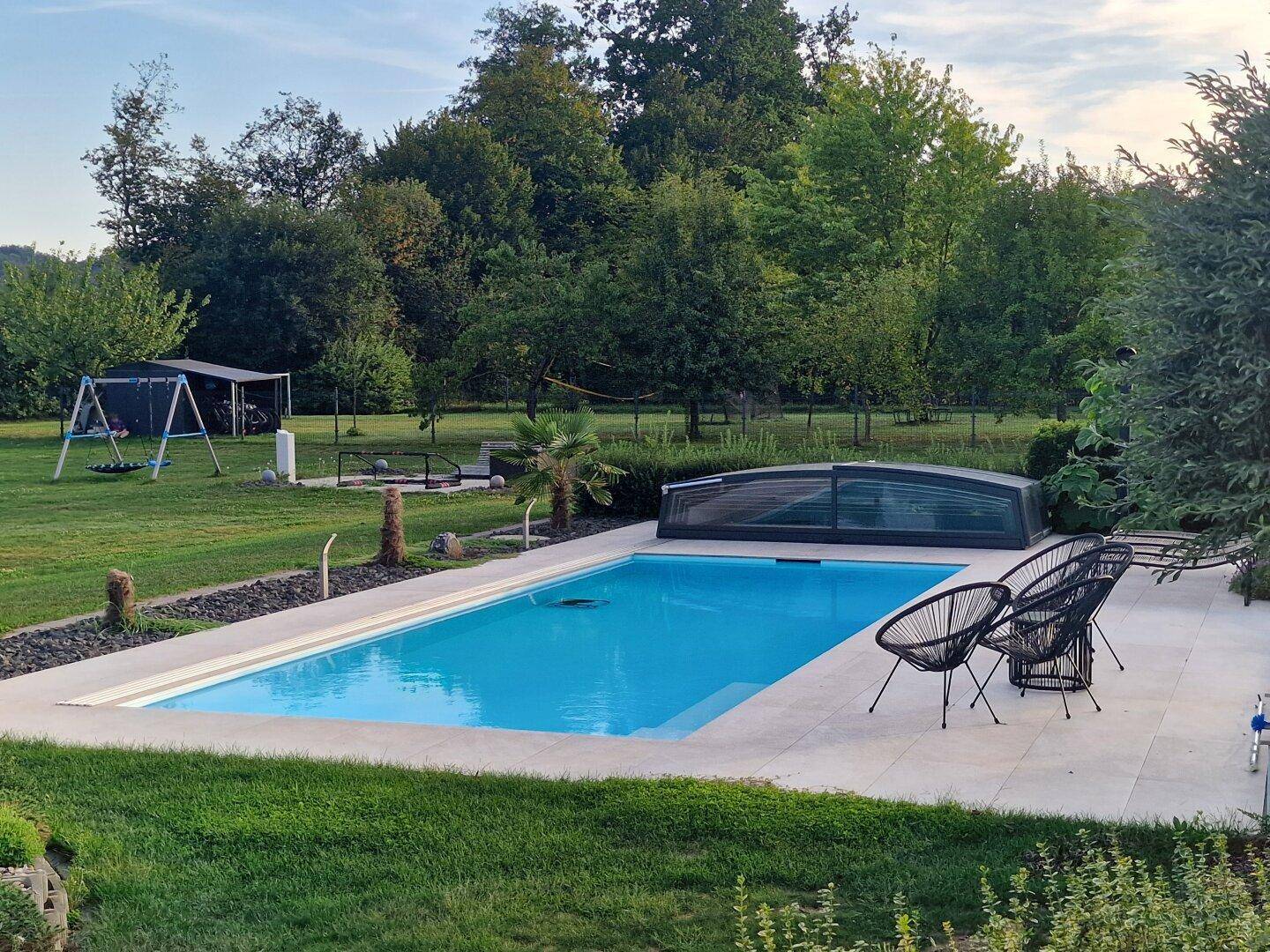 Großer Garten mit Swimmingpool, Liegefläche und Spielbereich im Hintergrund.