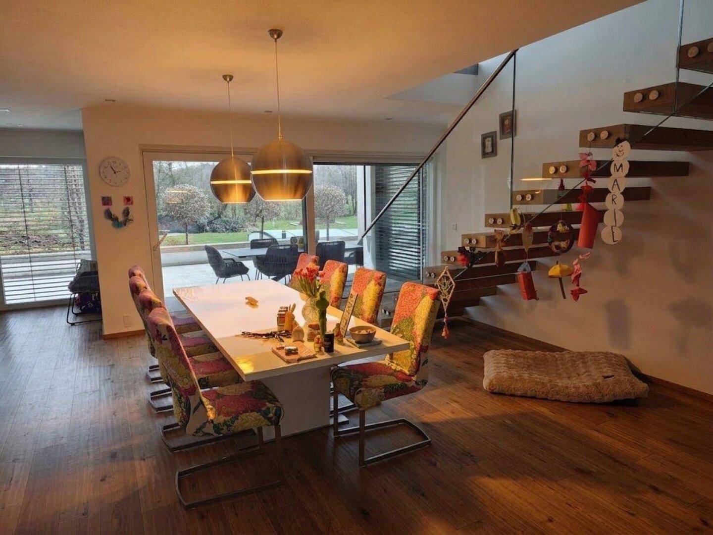 Geräumiger Essbereich mit Holzboden, moderner Treppe und Blick in den Garten.