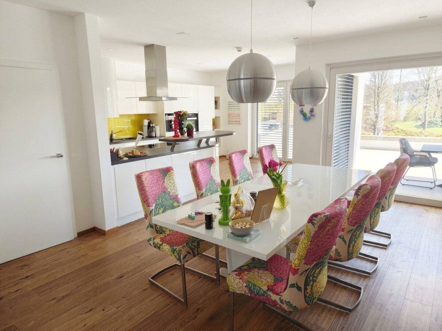 Heller offener Wohn-Essbereich mit moderner Küche, Holzboden und Zugang zur Terrasse.
