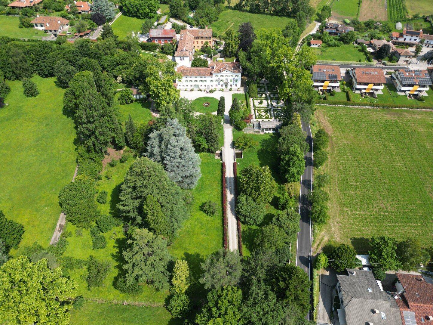 Umfassende Luftaufnahme des Anwesens, umgeben von Feldern und Bäumen, mit der Villa als Mittelpunkt.