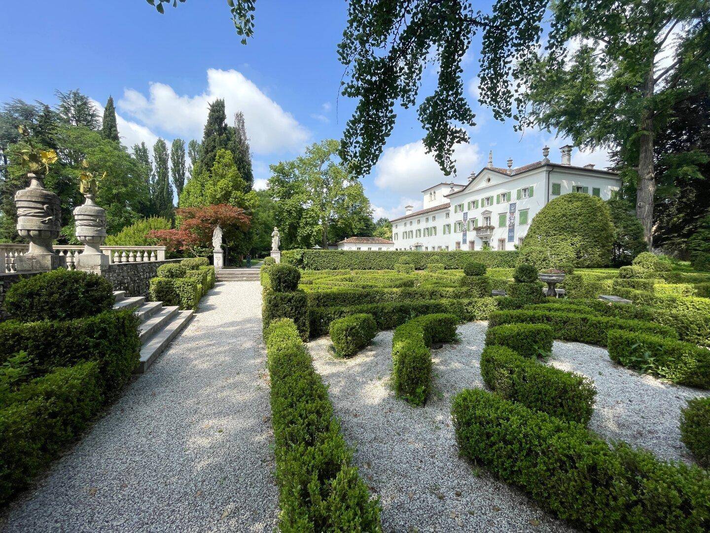 Der kunstvoll angelegte Barockgarten mit geschnittenen Buchsbaumhecken und steinernen Verzierungen vor der Villa.