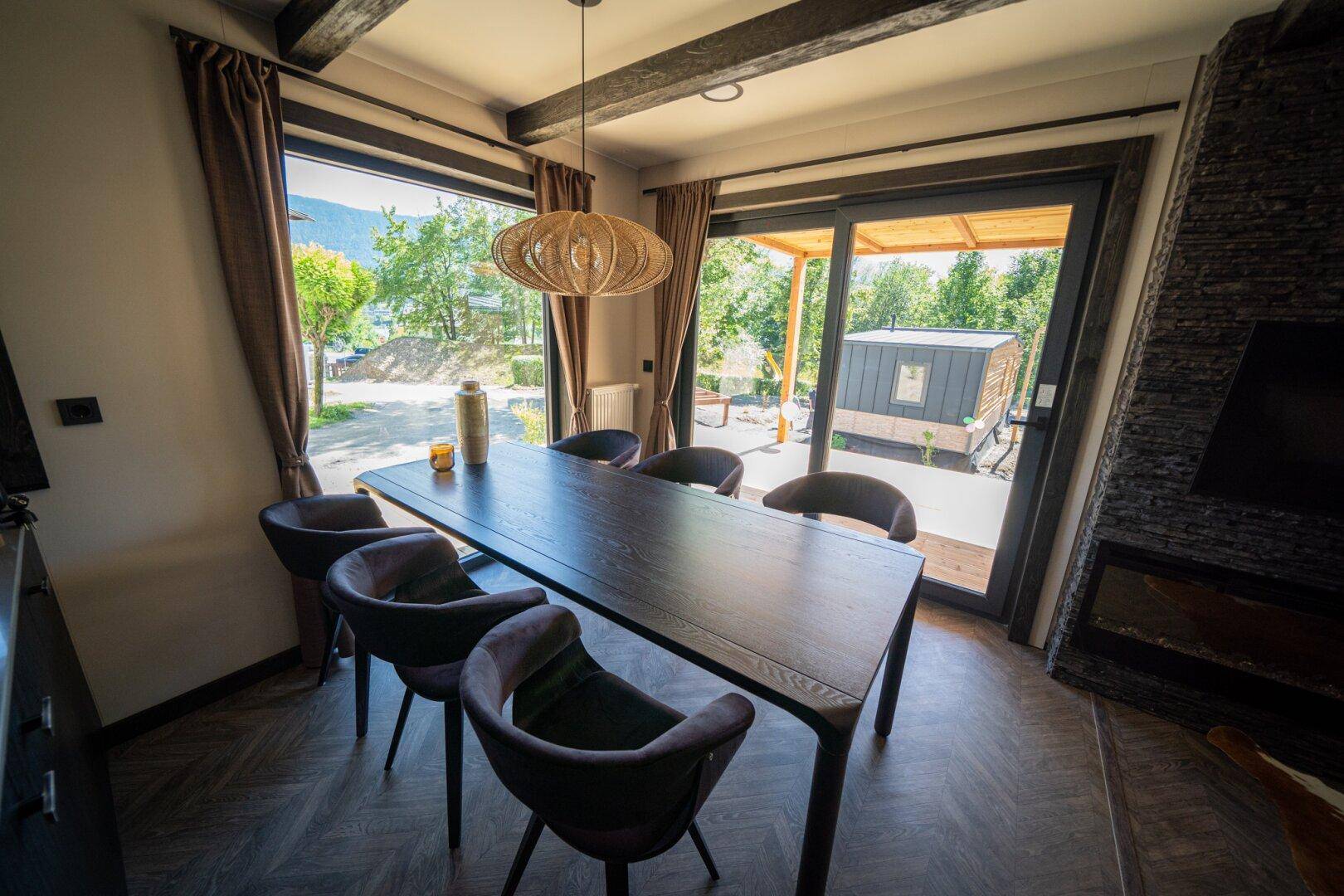 Eleganter Essbereich mit großem Holztisch, Kamin und Zugang zur überdachten Terrasse.
