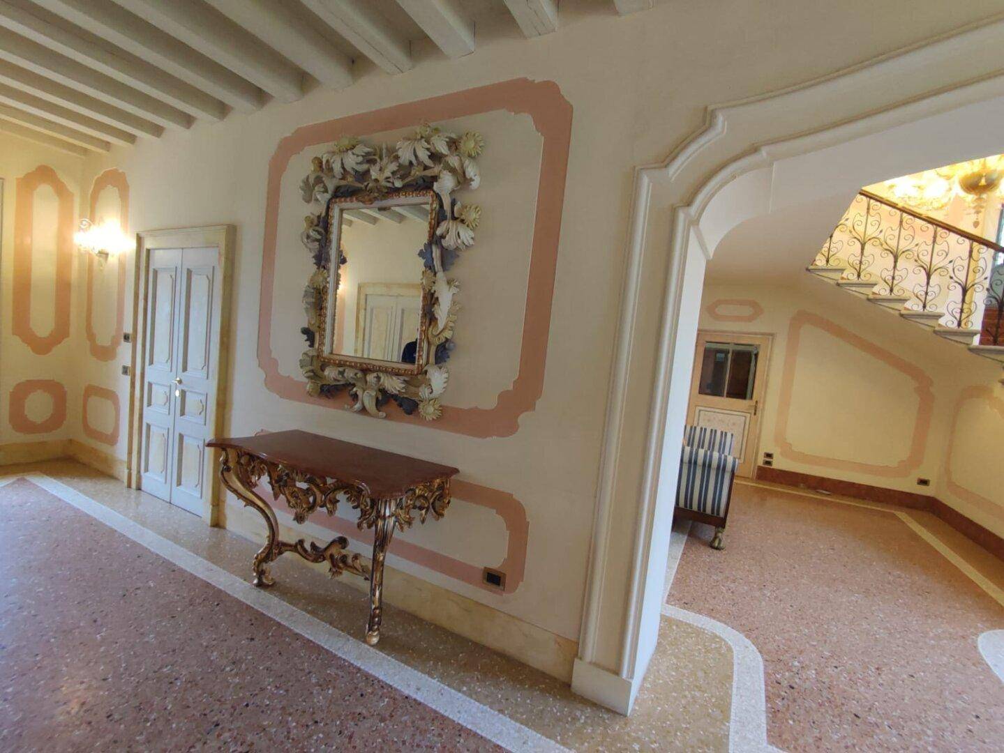 Großzügige Diele mit Terrazzoboden, einer verzierten Konsole und einem kunstvoll geschnitzten Spiegel an der Wand.