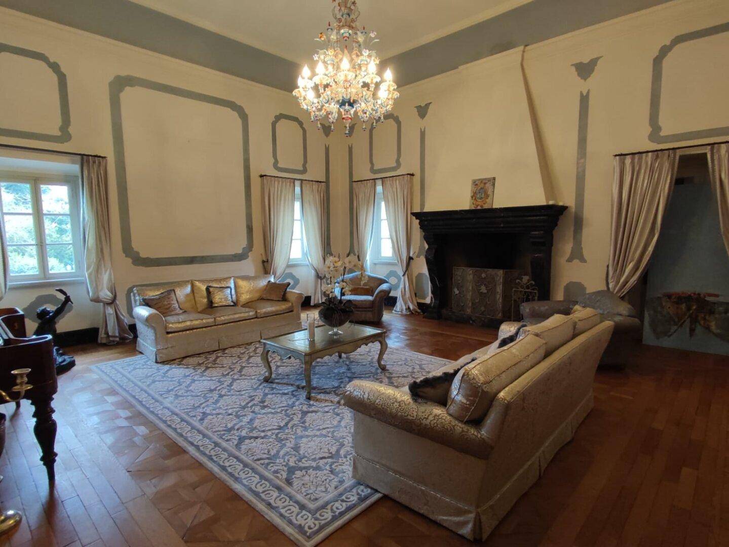 Luxuriöses Wohnzimmer mit großem Kamin, eleganten Sofas und einem gemusterten Teppich, der den Raum schmückt.