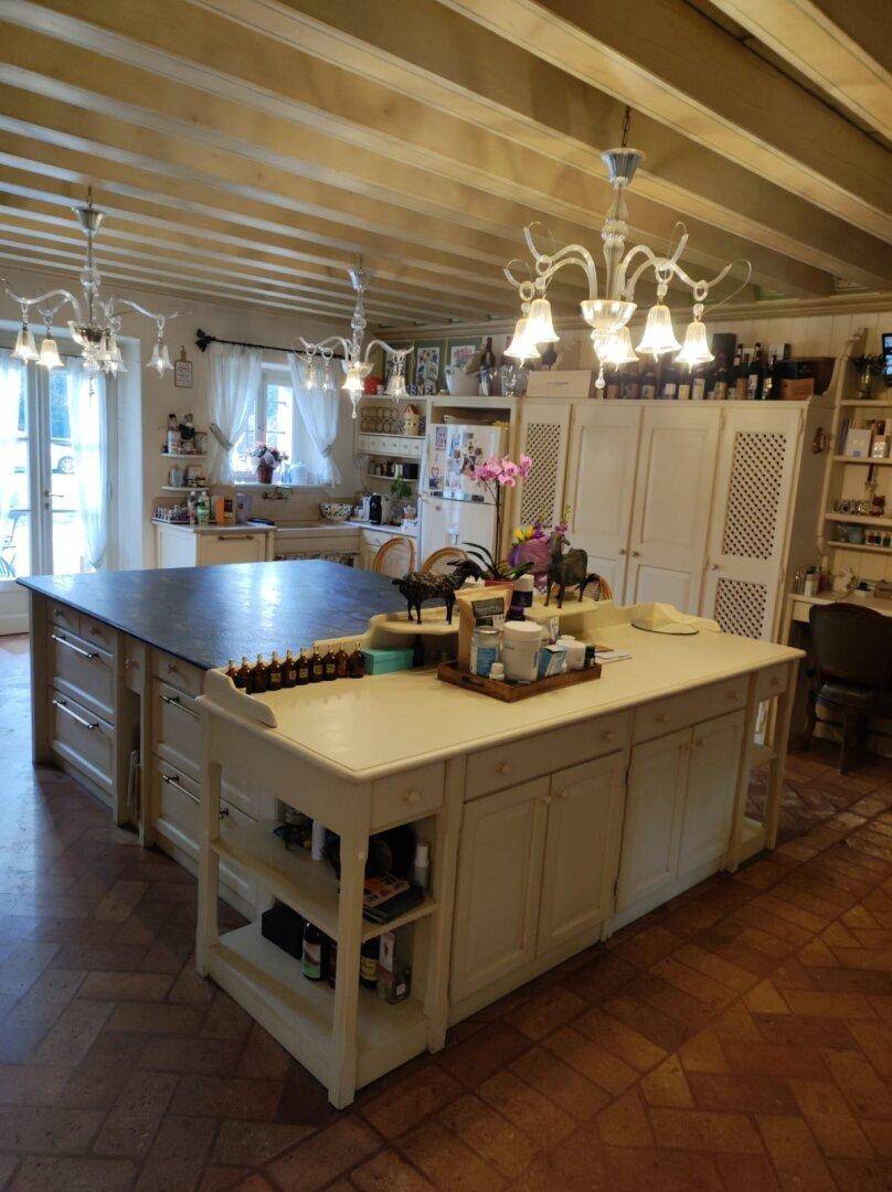 Große Landhausküche mit zwei Kochinseln, Terrakottaboden und Holzbalkendecke, ideal für geselliges Kochen.