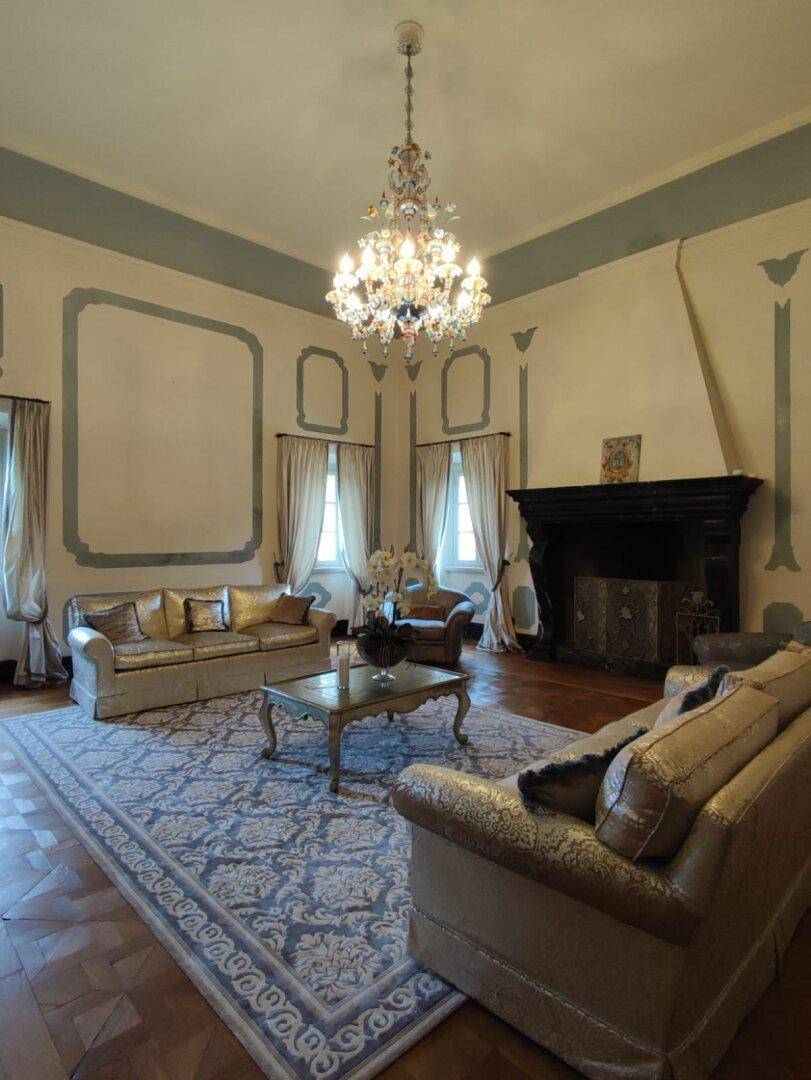 Luxuriöses Wohnzimmer mit großem Kamin, eleganten Sofas und einem gemusterten Teppich, der den Raum schmückt.
