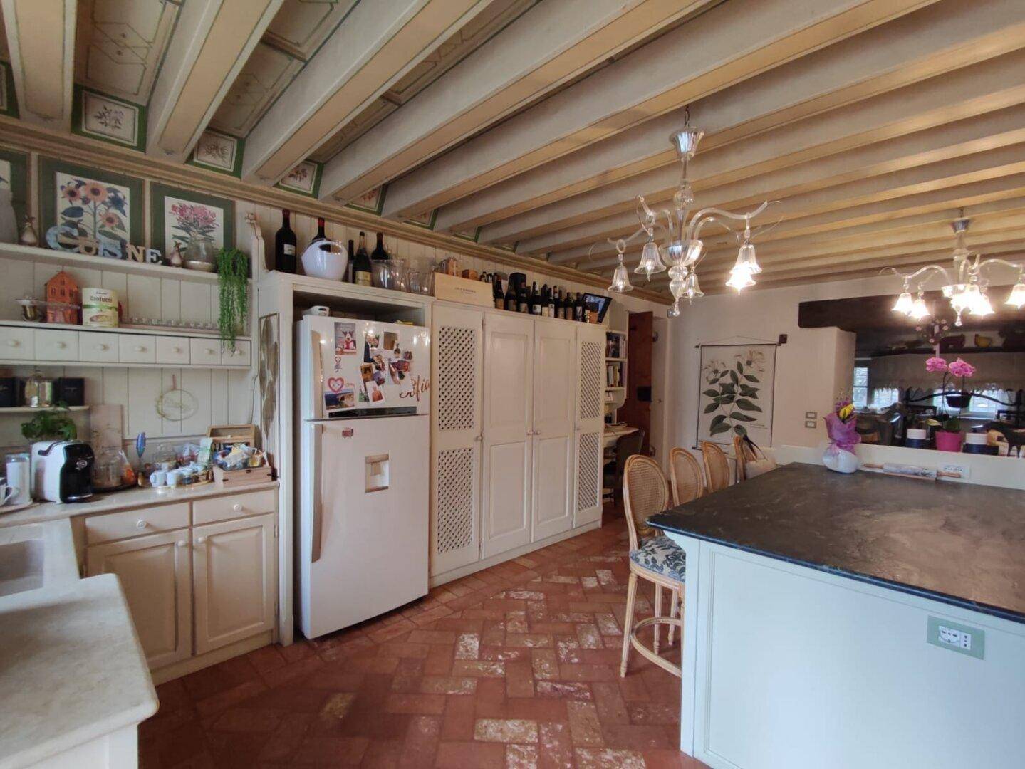Helle Küche mit Kühlschrank, Einbauschränken und Terrakottaboden, die eine warme und einladende Atmosphäre bietet.