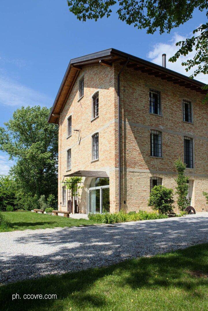 Ansicht des Ziegelsteinhauses von der Seite mit großen Fenstern und einem gepflegten Kiesweg.