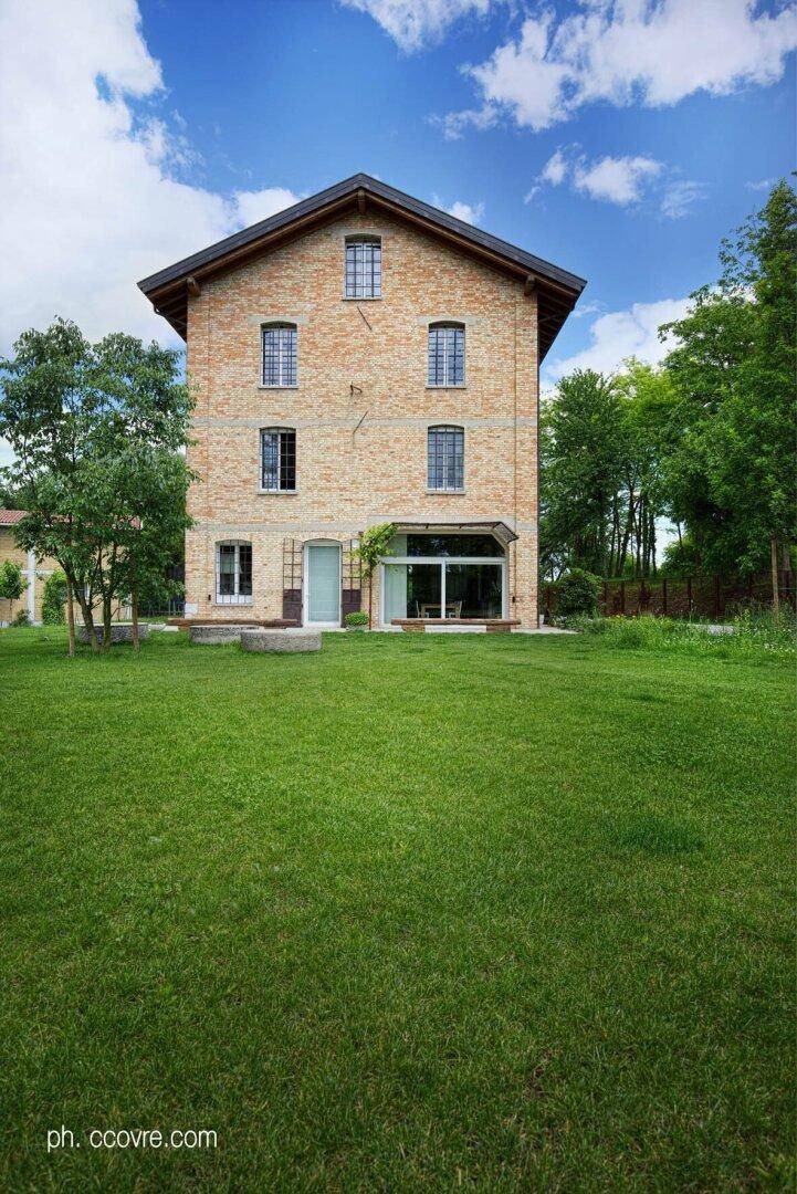 Das Ziegelsteinhaus von hinten mit einem großen, gepflegten Rasen und einem weiten Blick ins Grüne.