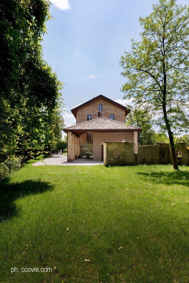 Weitläufiger Gartenbereich hinter dem Ziegelsteinhaus mit gepflegtem Rasen und altem Baumbestand.
