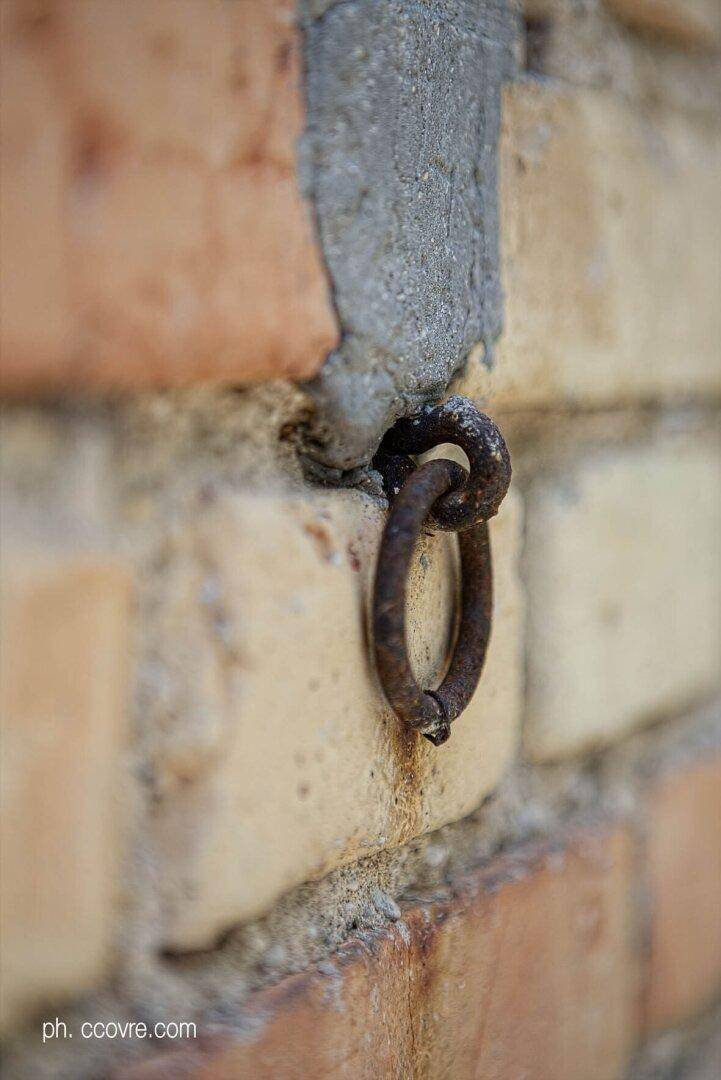 Rostiger Metallring in einer alten Backsteinwand, der an historische Nutzung erinnert.