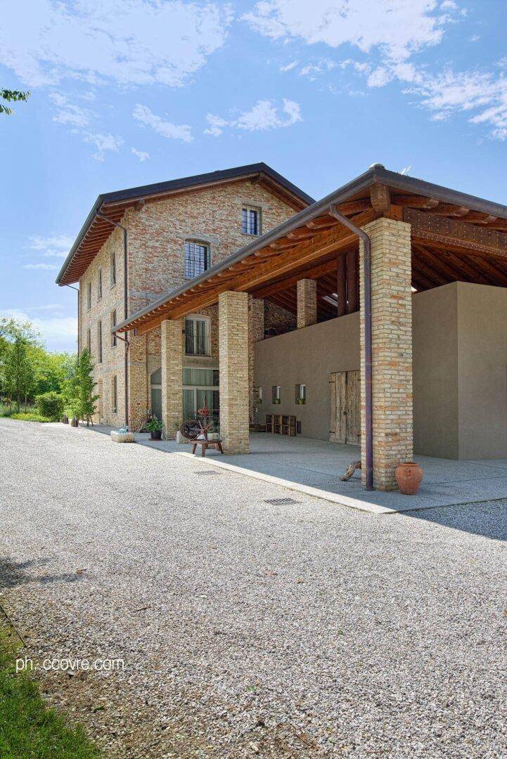 Das Ziegelsteinhaus mit breitem Kiesweg und einem überdachten Bereich, der von massiven Säulen getragen wird.