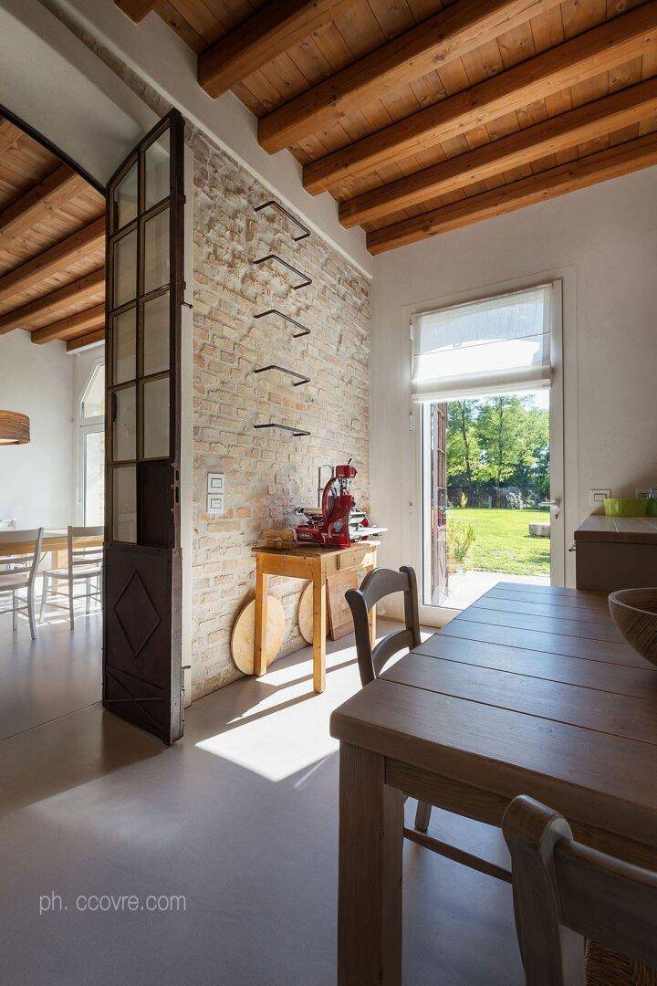 Heller Essbereich mit Holztisch, Zugang zum Garten und sichtbaren Holzbalken an der Decke.
