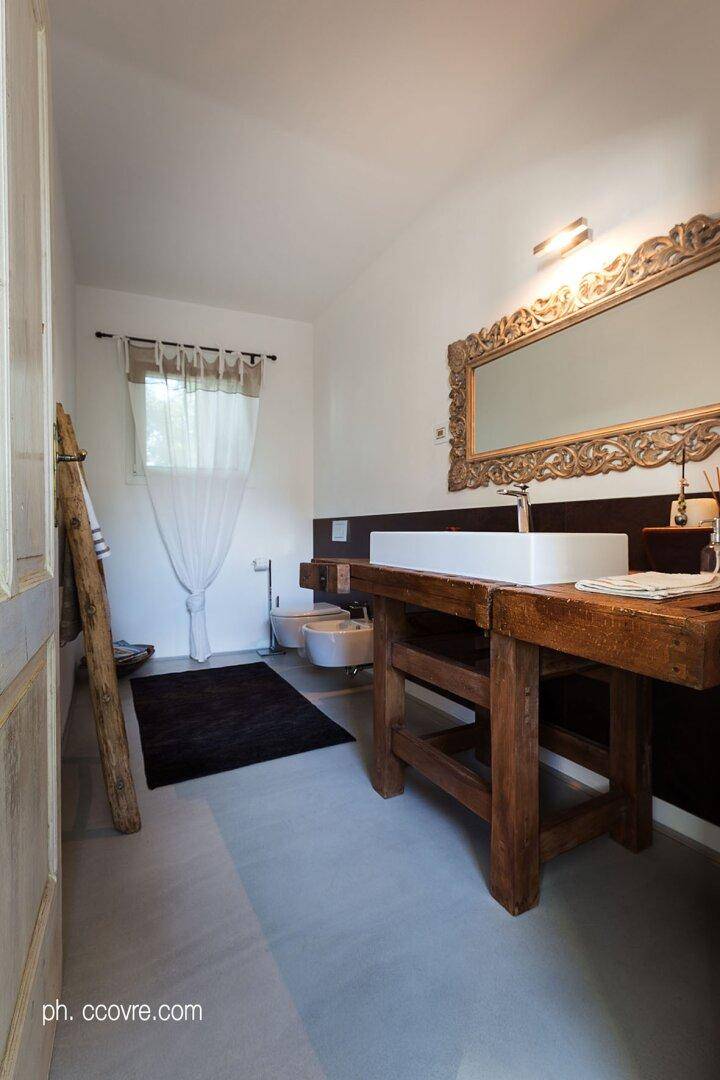 Modernes Badezimmer mit rustikalem Holzwaschtisch, großem Zierspiegel und Fenster mit Vorhang.