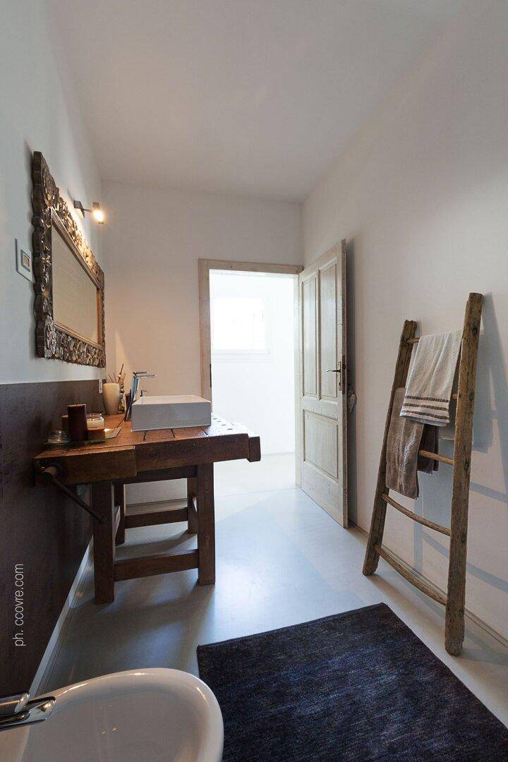 Modernes Badezimmer mit Einzelwaschbecken auf einem Holztisch und einem rustikalen Handtuchhalter.