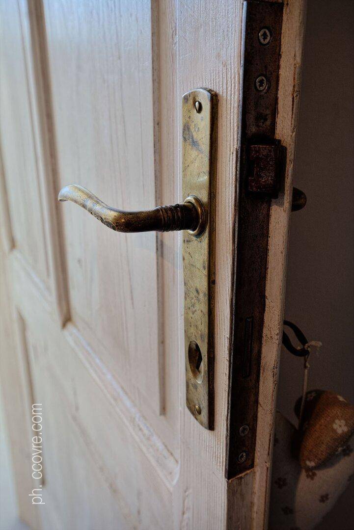 Nahaufnahme einer antiken Tür mit einem verzierten Türgriff aus Metall.
