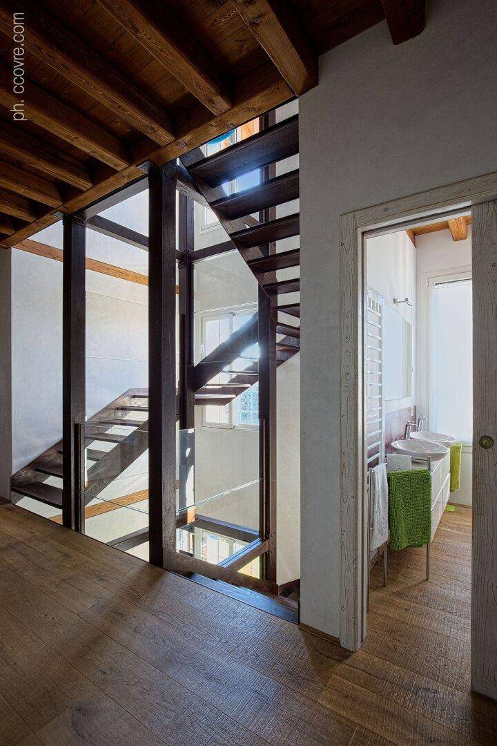 Heller Flurbereich mit moderner Treppe und Blick in ein Badezimmer mit Doppelwaschbecken.