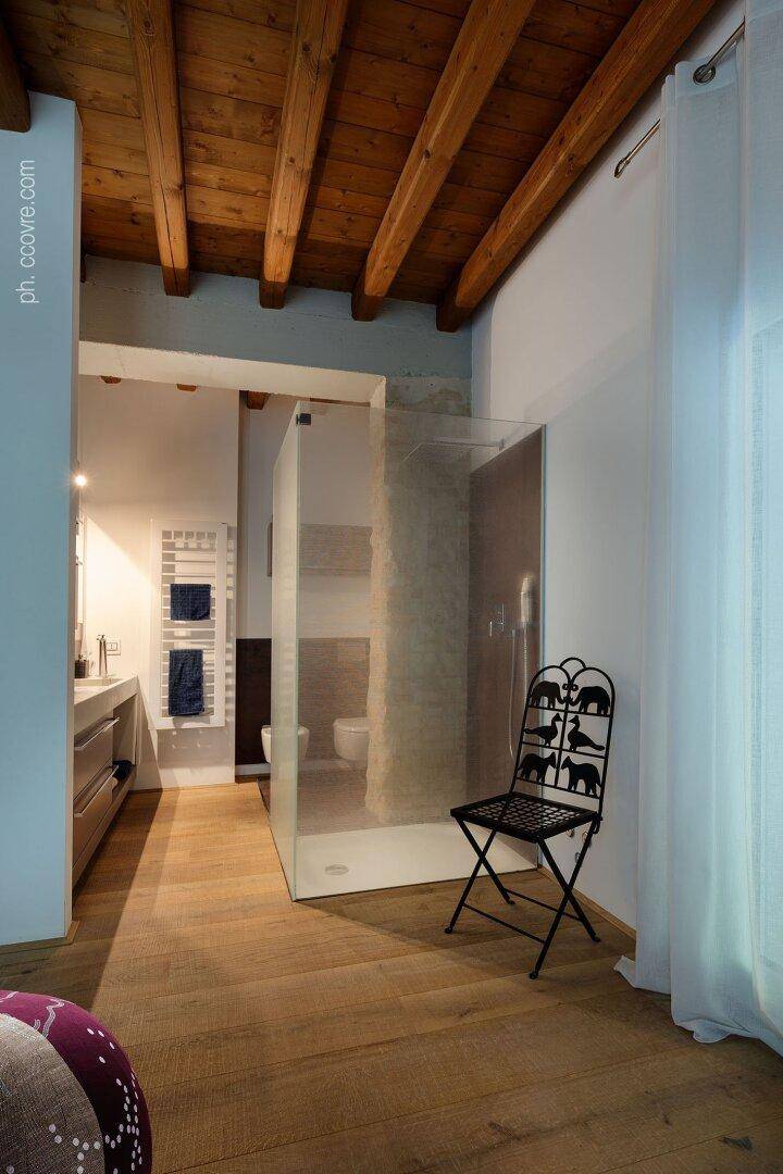 Geräumiges Badezimmer mit Holzbalkendecke, begehbarer Dusche und modernem Doppelwaschbecken.
