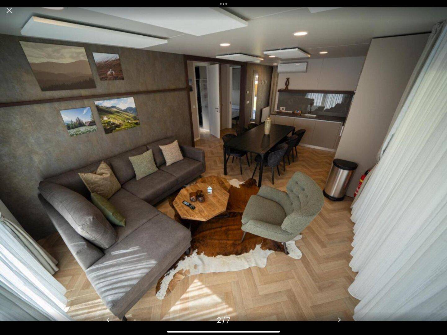 Offener Wohn- und Essbereich mit modernem Sofa, Esstisch und Fischgrätparkettboden.