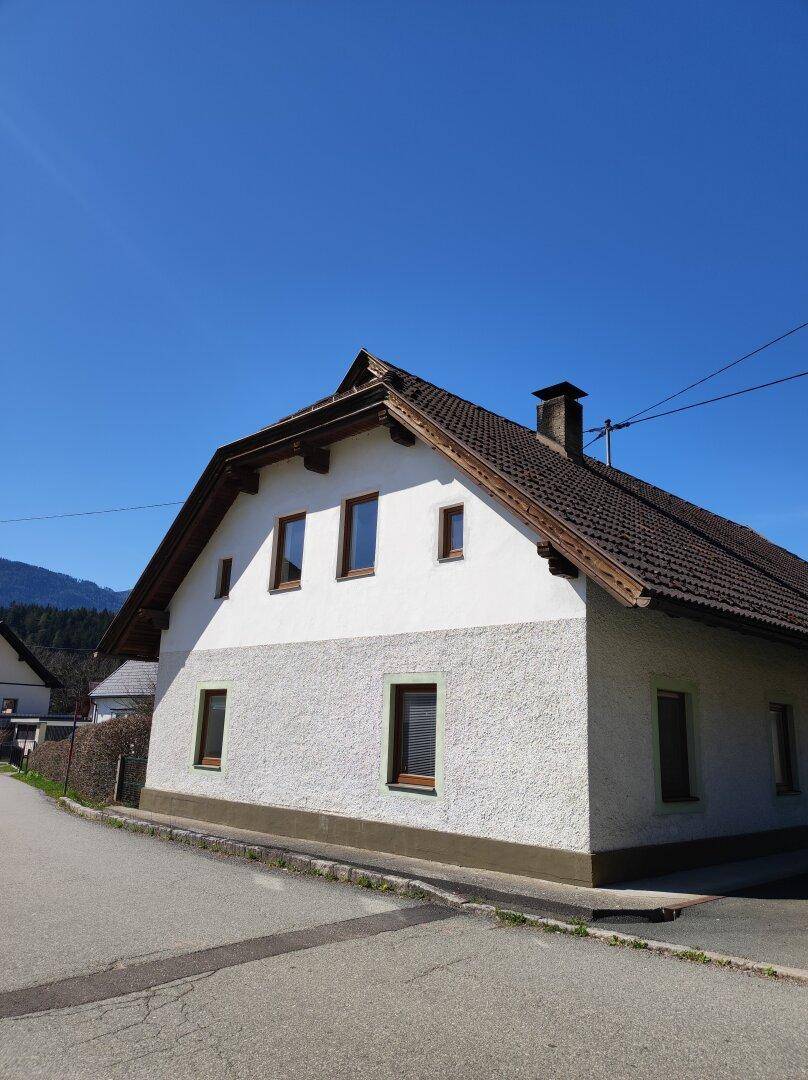 Seitenansicht des Hauses mit traditioneller Fassade, Satteldach und Fenstern zur Straße hin.