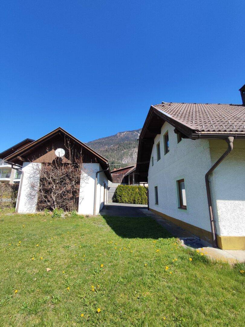 Ansicht des Haupthauses und eines Nebengebäudes mit Zufahrt und Garten in ländlicher Umgebung.