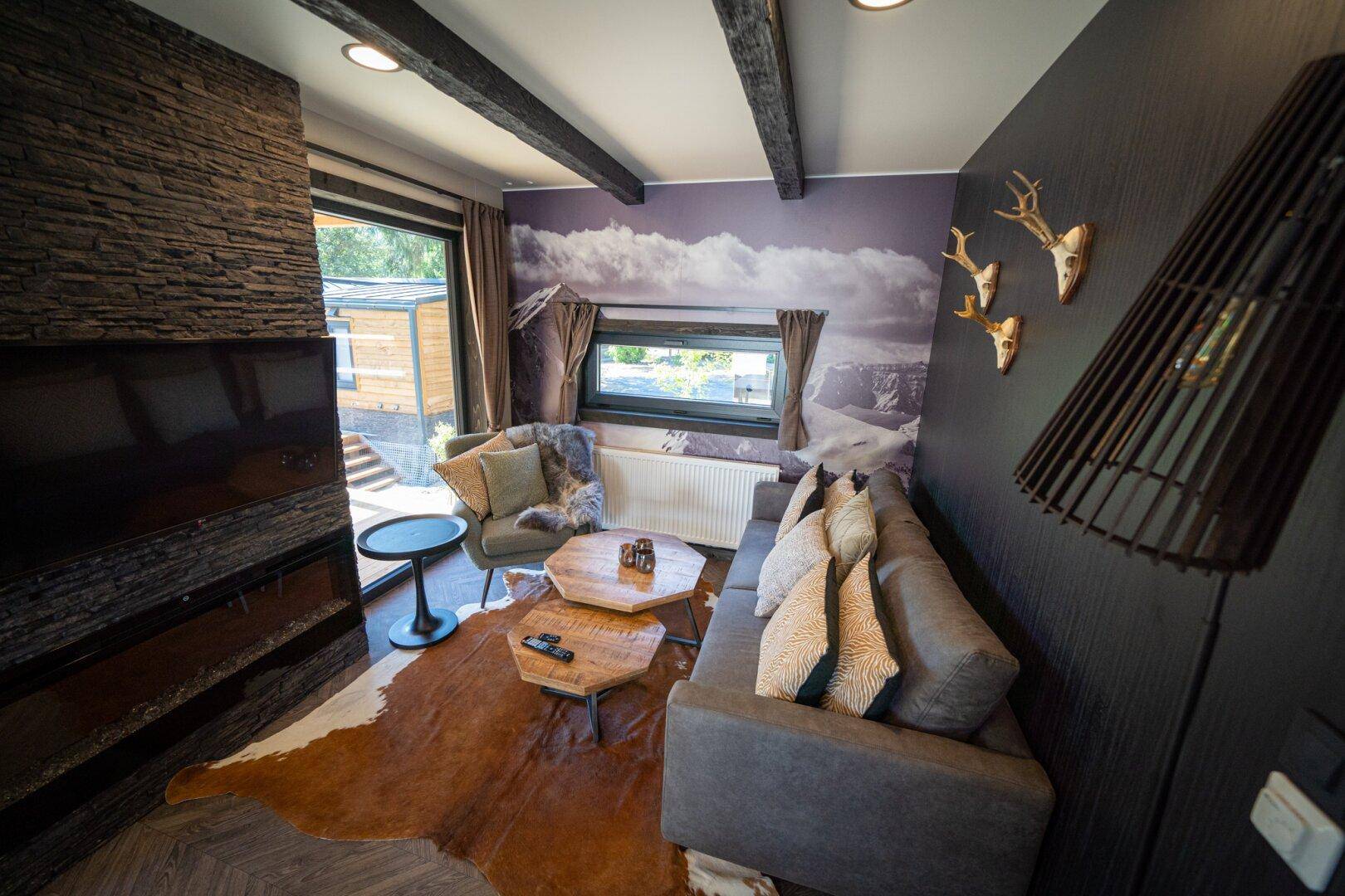 Gemütliches Wohnzimmer mit Steinwand, Fernseher und alpiner Dekoration.