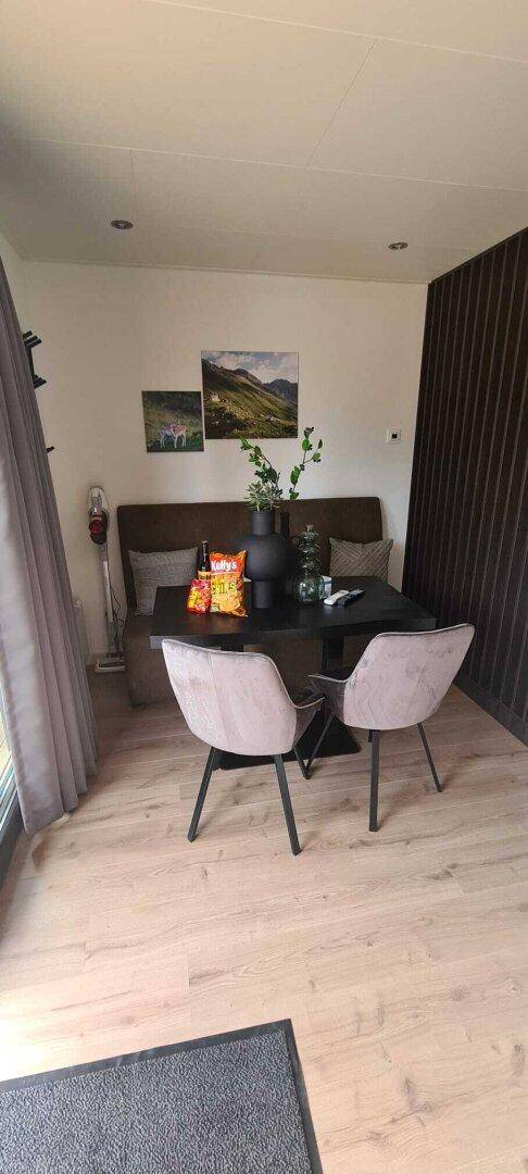 Heller Essbereich mit modernem Tisch, bequemen Stühlen und Holzakzenten an der Wand.