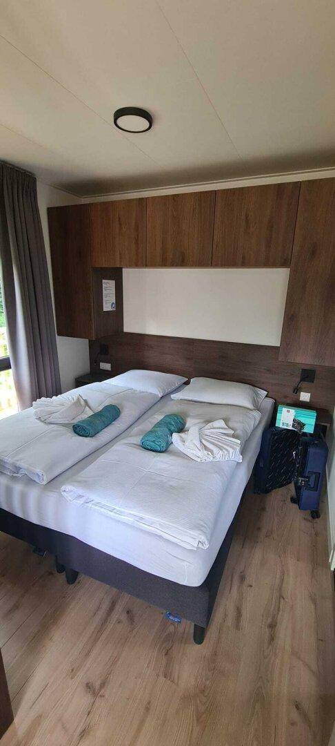 Gemütliches Schlafzimmer mit zwei Einzelbetten, Holzmöbeln und Fenster mit Vorhängen.