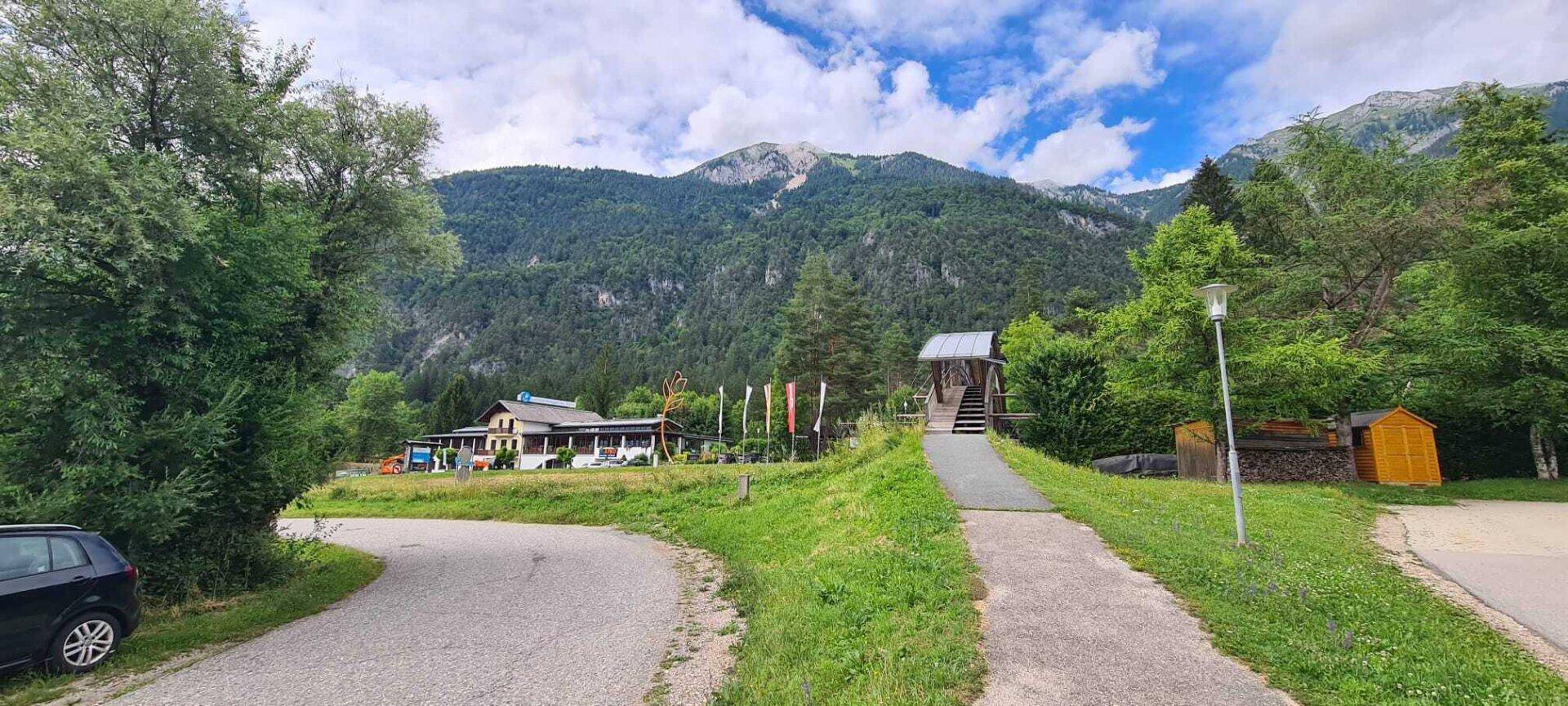 Zufahrtsweg zum Hauptgebäude des Ferienparks, umgeben von grüner Landschaft und Bergen.